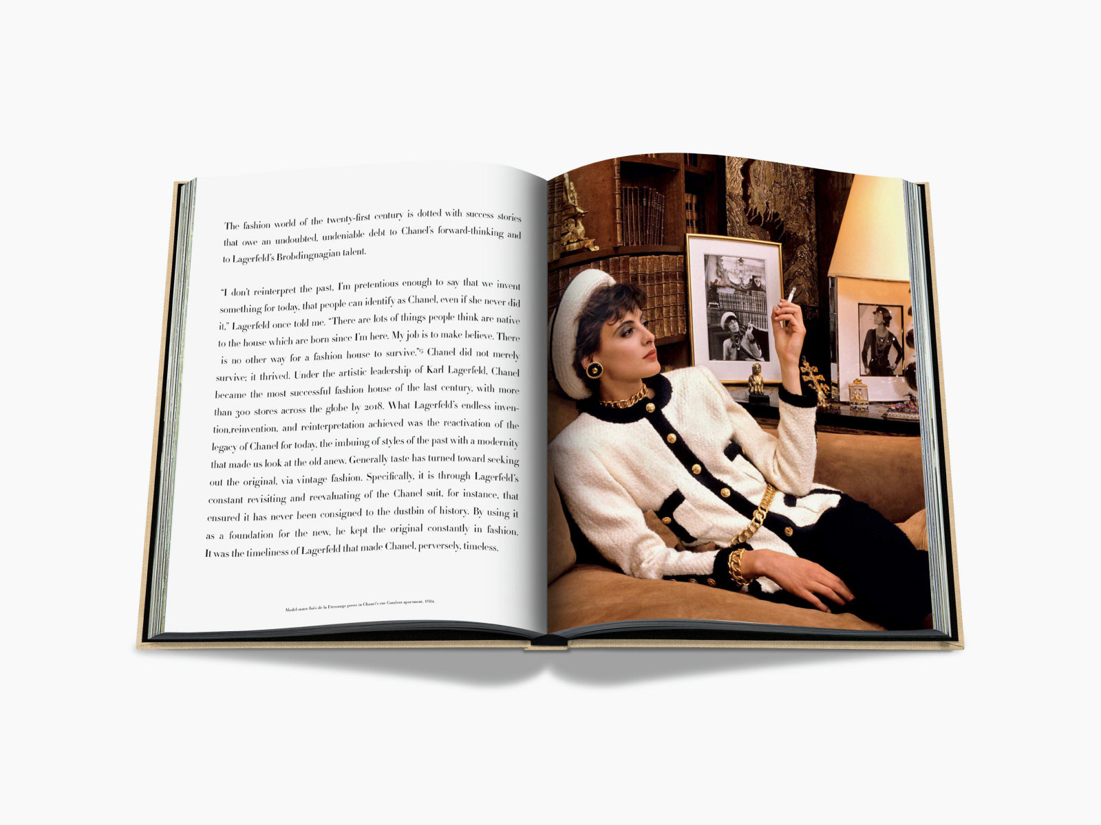 Model reclines on a sofa in a white bouclé jacket with black trim and gold jewelry in a Chanel inspired room