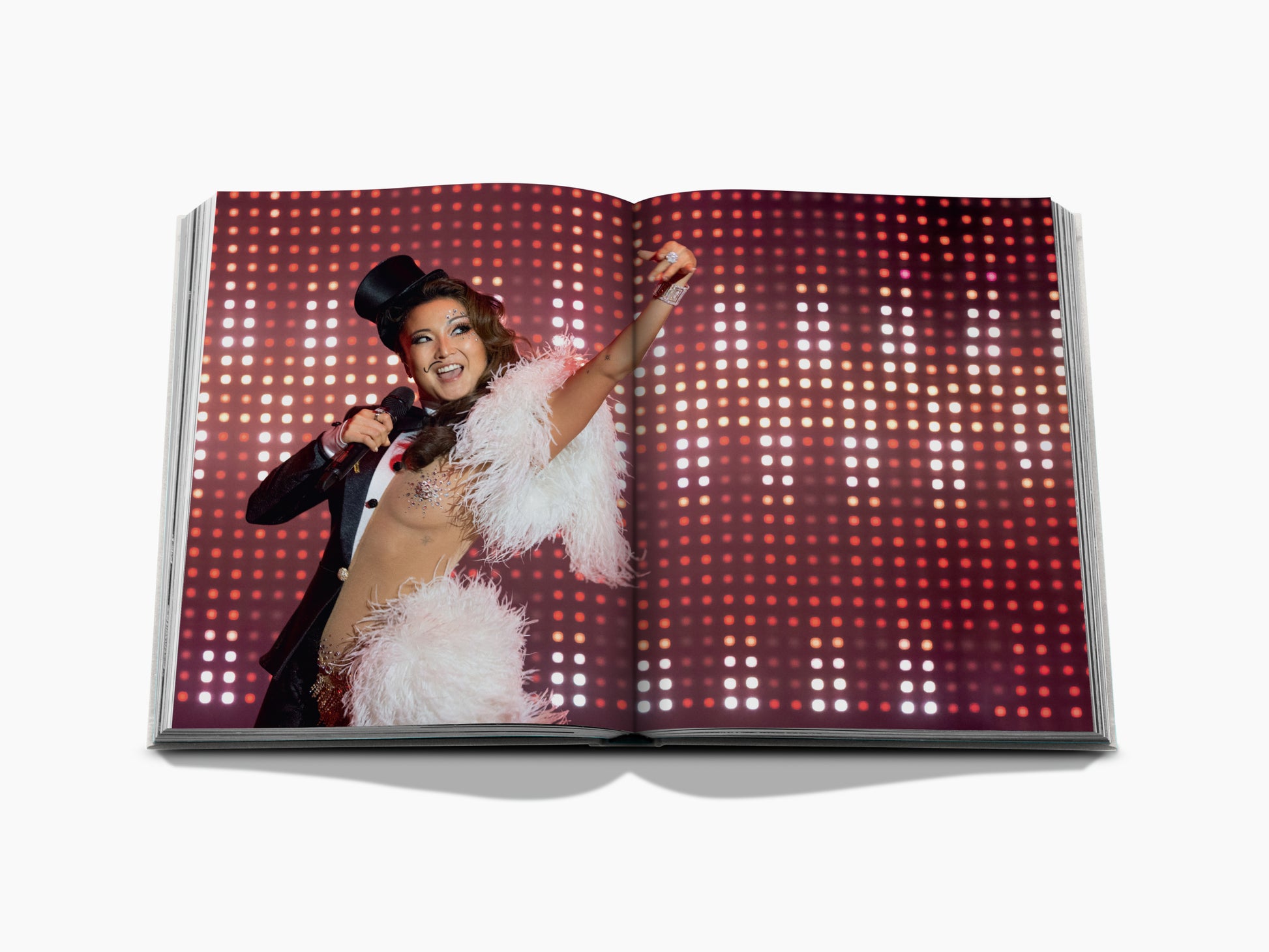 Spread from Emily in Paris The Fashion Guide featuring a stage performer in a white feather boa and top hat on a red backdrop