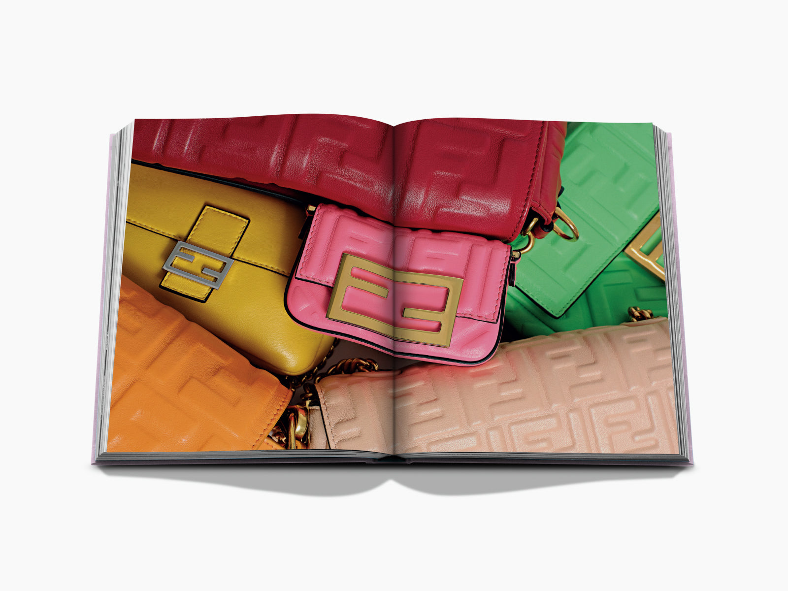 Colorful collage of stacked luxury handbags on a double page spread from Fashionphile The Book of Iconic Bags
