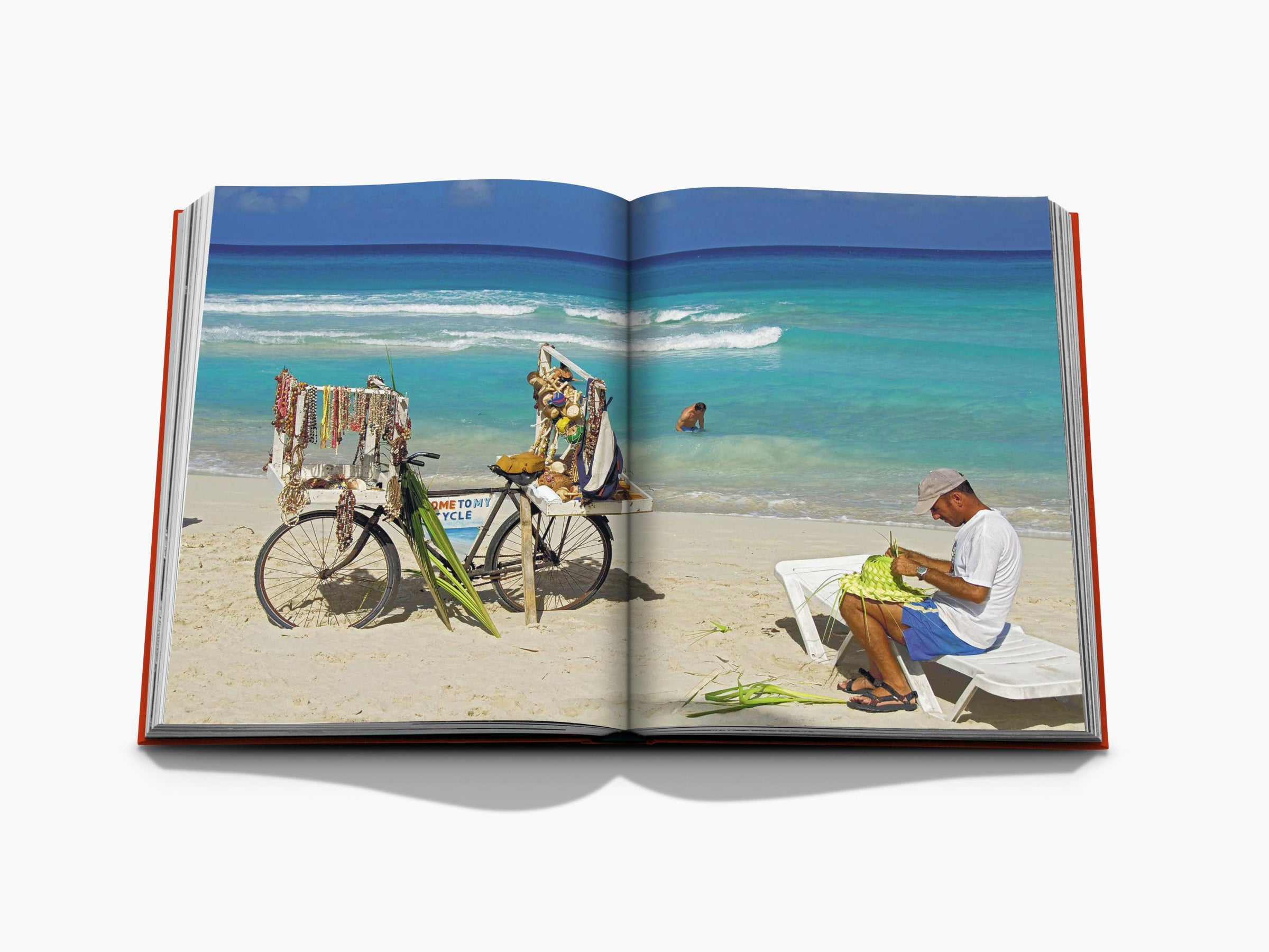 Cuban beach scene with a vendor cart of jewelry on the sand and a man weaving crafts as turquoise waves roll in