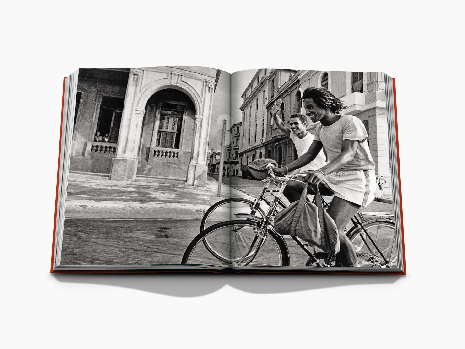 Open book with a black and white city street scene on the left and a lit ornate building framed by palm trees on the right.