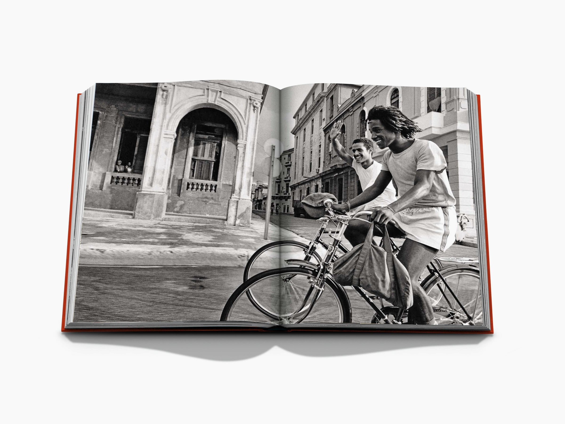 Open book with a black and white city street scene on the left and a lit ornate building framed by palm trees on the right.