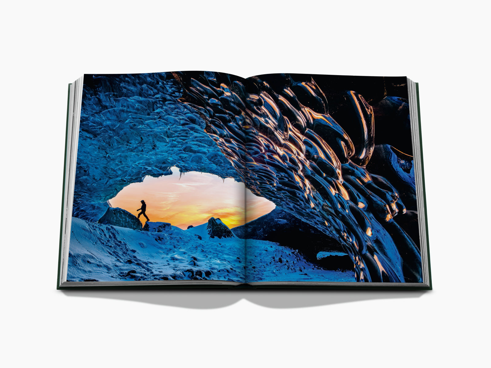Ice cave photograph with a climber on blue ice beside a sunset glow