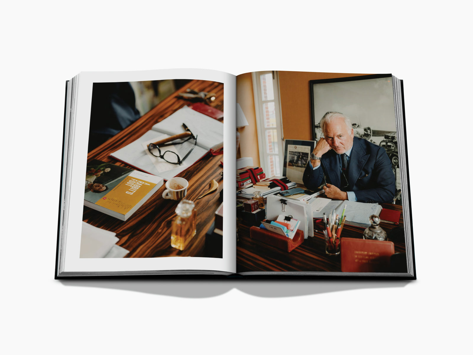 Two-page spread from London Chic showing a cluttered desk with glasses, a yellow book, a coffee cup, and a suited man.