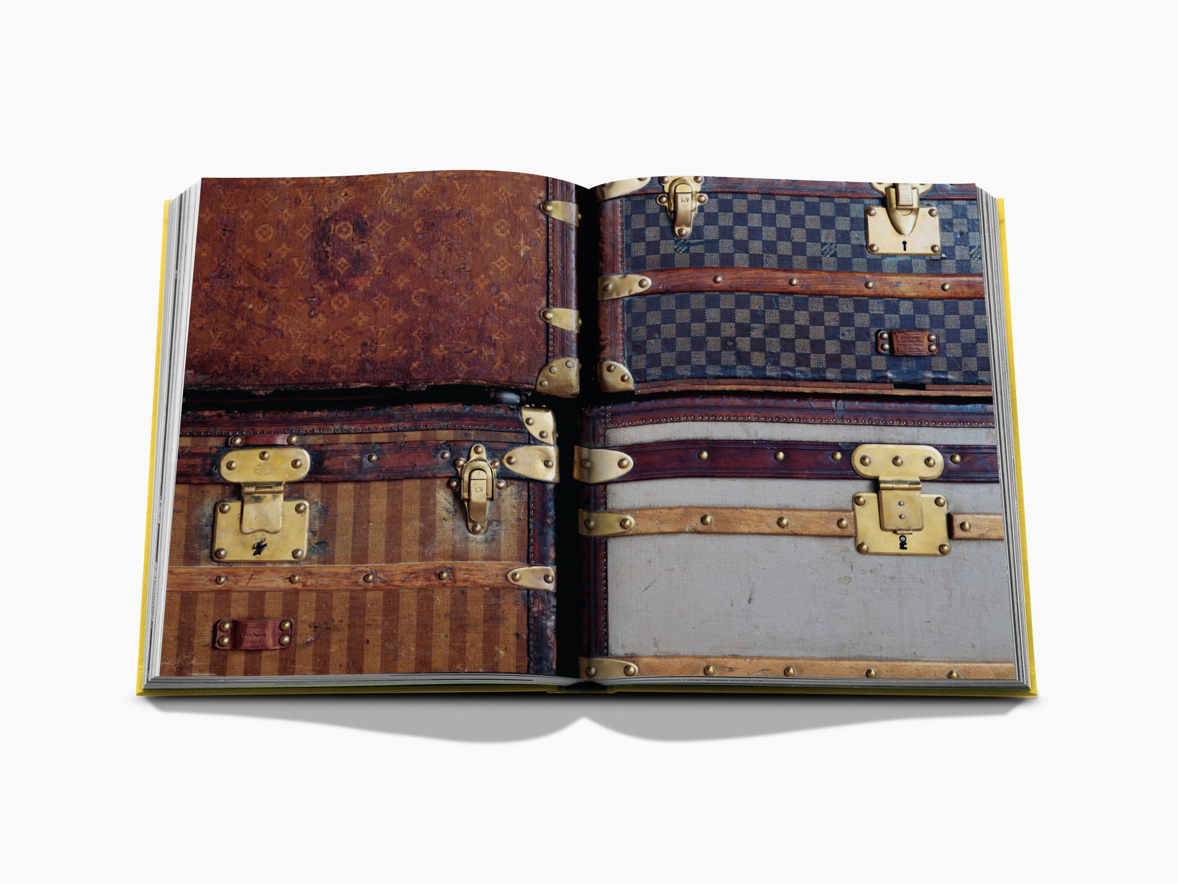 Two page spread shows stacked vintage Louis Vuitton luggage across both pages.