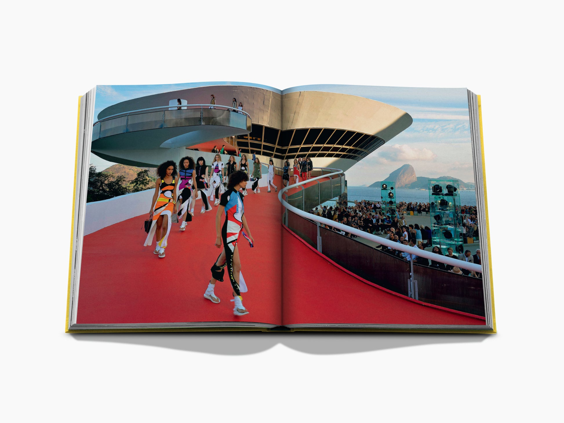 Open From Louis to Vuitton spread depicting a circular modern pavilion on the left and a runway with models against a seaside backdrop on the right.