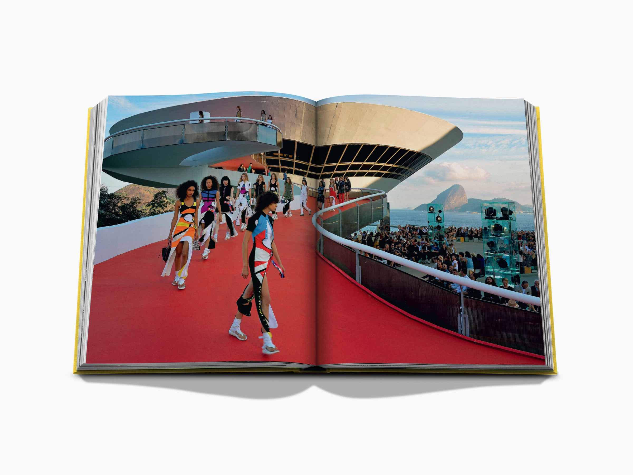 Open From Louis to Vuitton spread depicting a circular modern pavilion on the left and a runway with models against a seaside backdrop on the right.