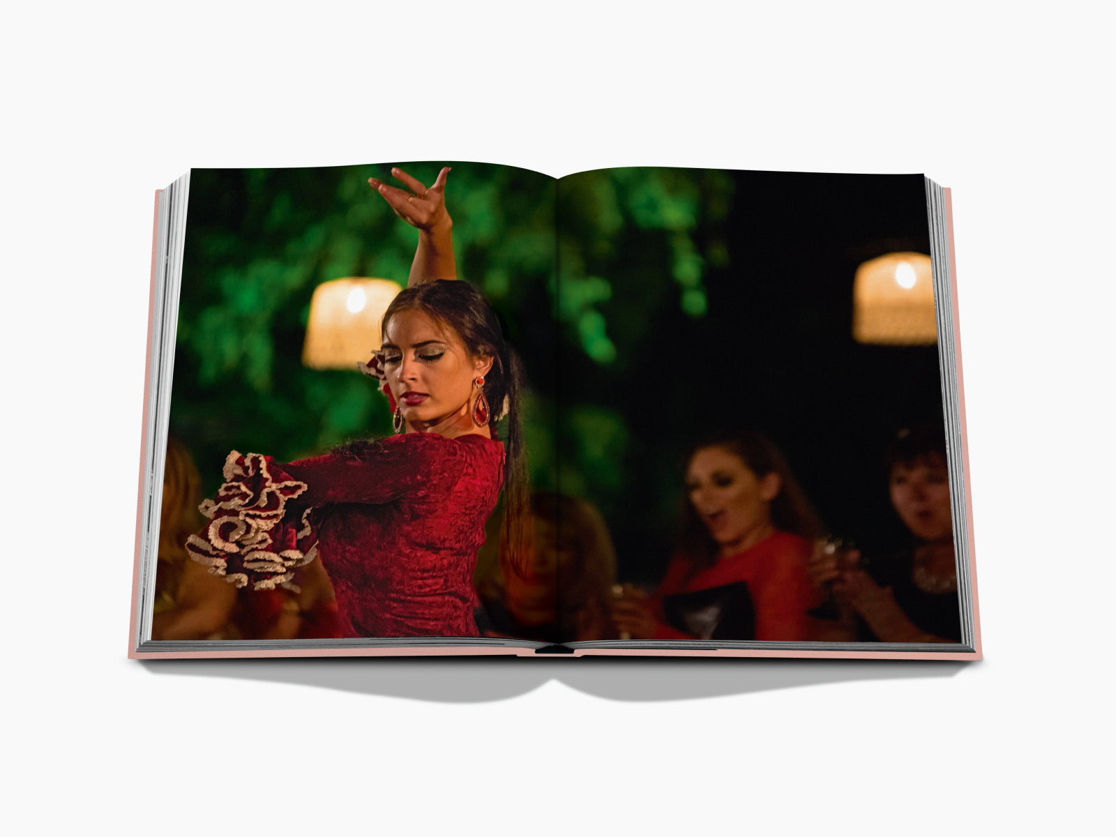 Flamenco dancer in a red dress performing at an evening event with a green backdrop and guests in the background.