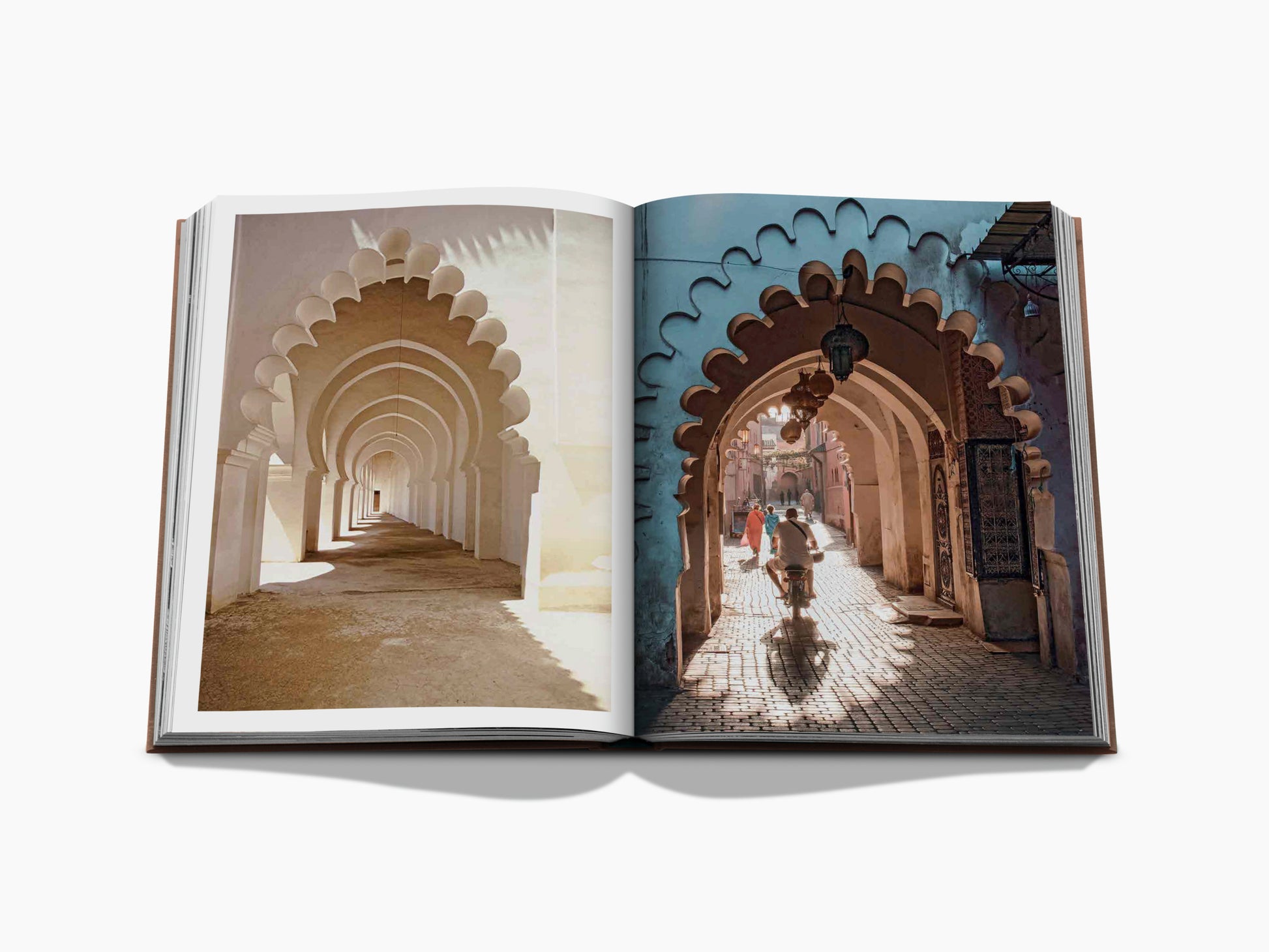 Open Marrakech Flair book spread with a sunlit corridor of Moorish arches on the left and a shaded archway street with a cyclist on the right.