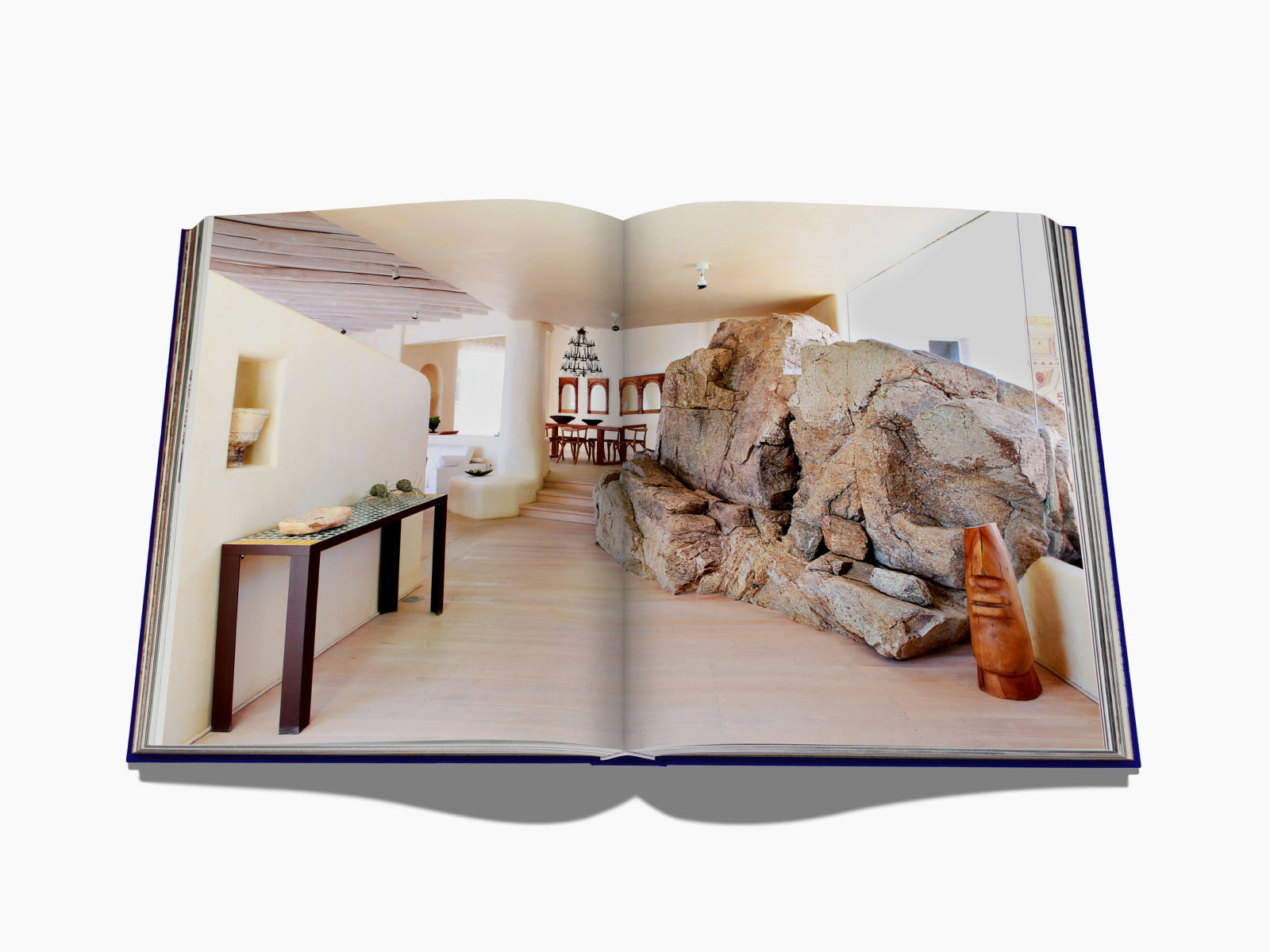 Open book spread featuring an interior with a large rock centerpiece, light walls, and minimalist furnishings.