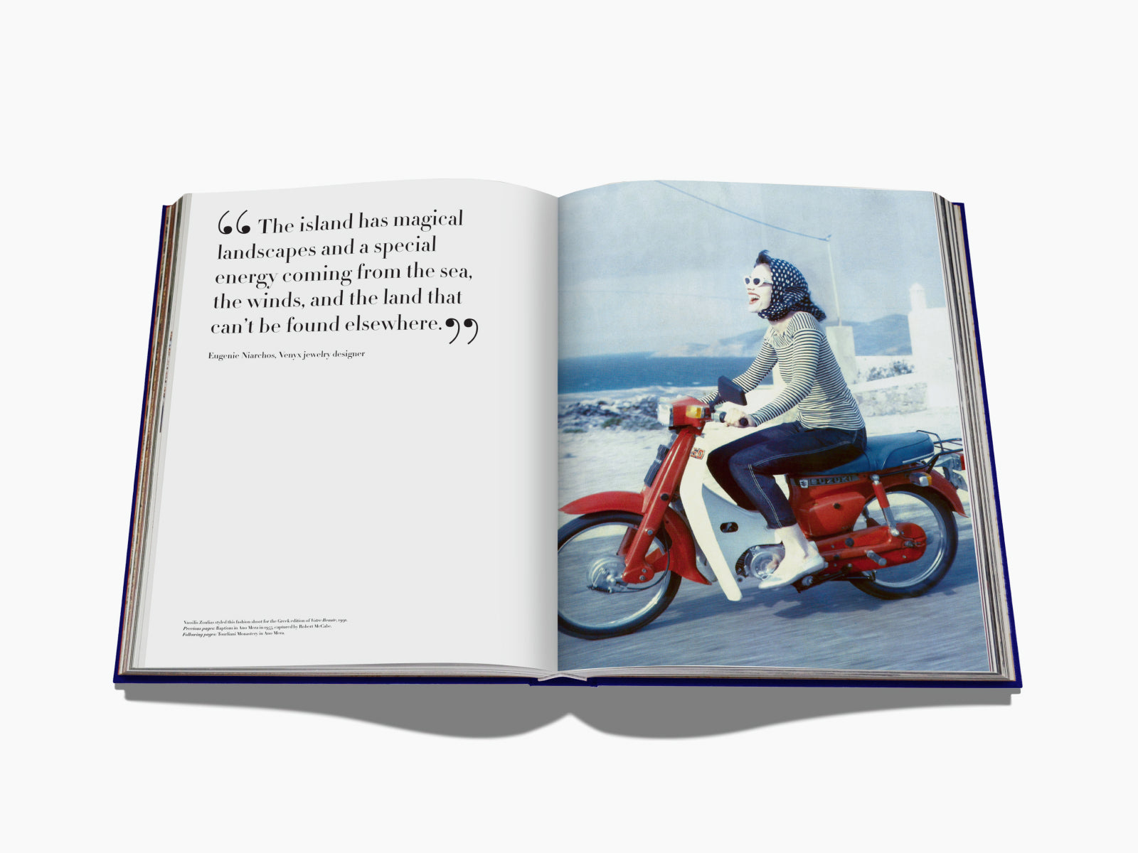 Color photo of a person riding a red motorcycle along a coastal road wearing a striped shirt and headscarf