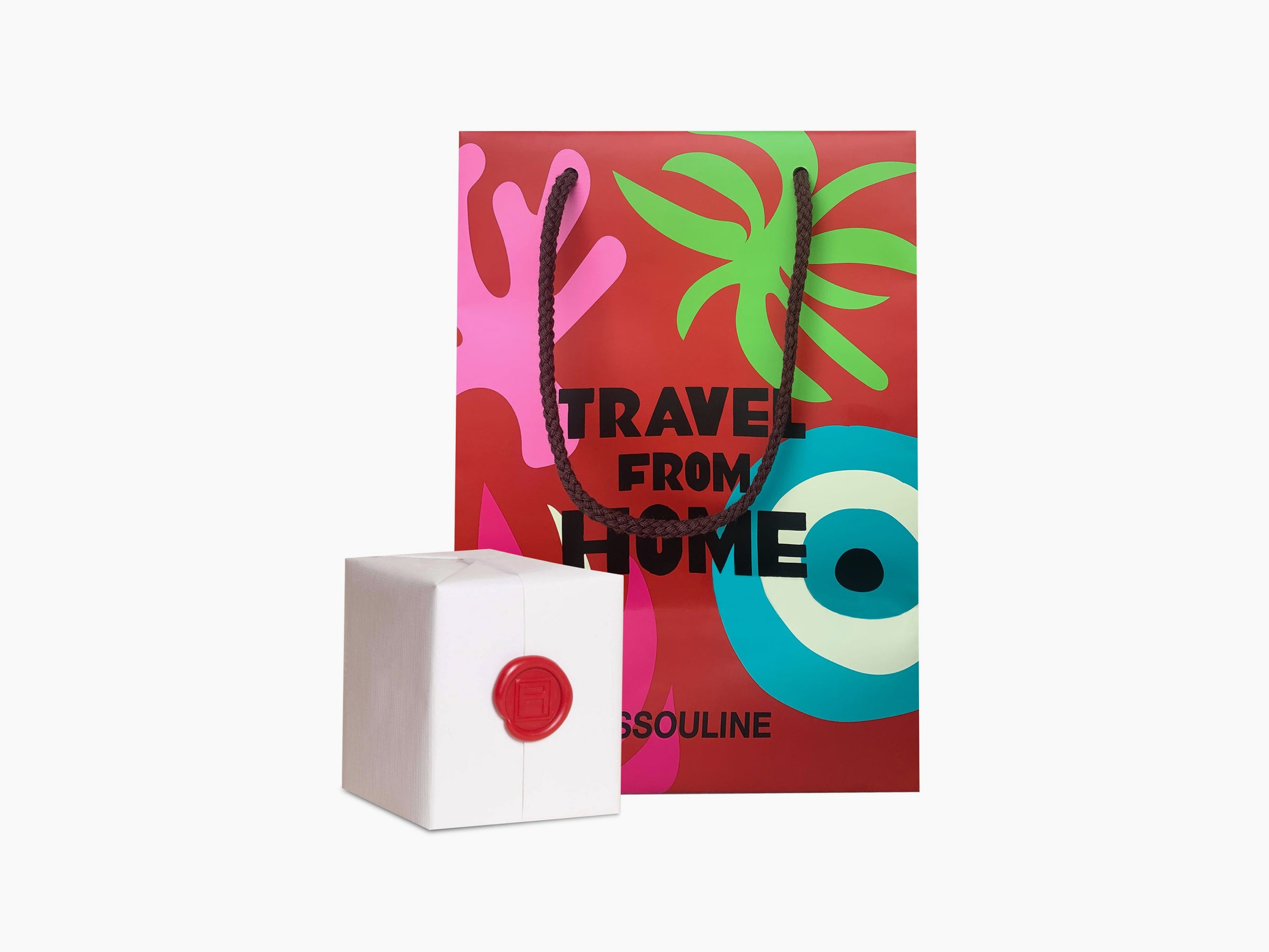 Bright Travel From Home gift bag with rope handles beside a small white gift box sealed with red wax.