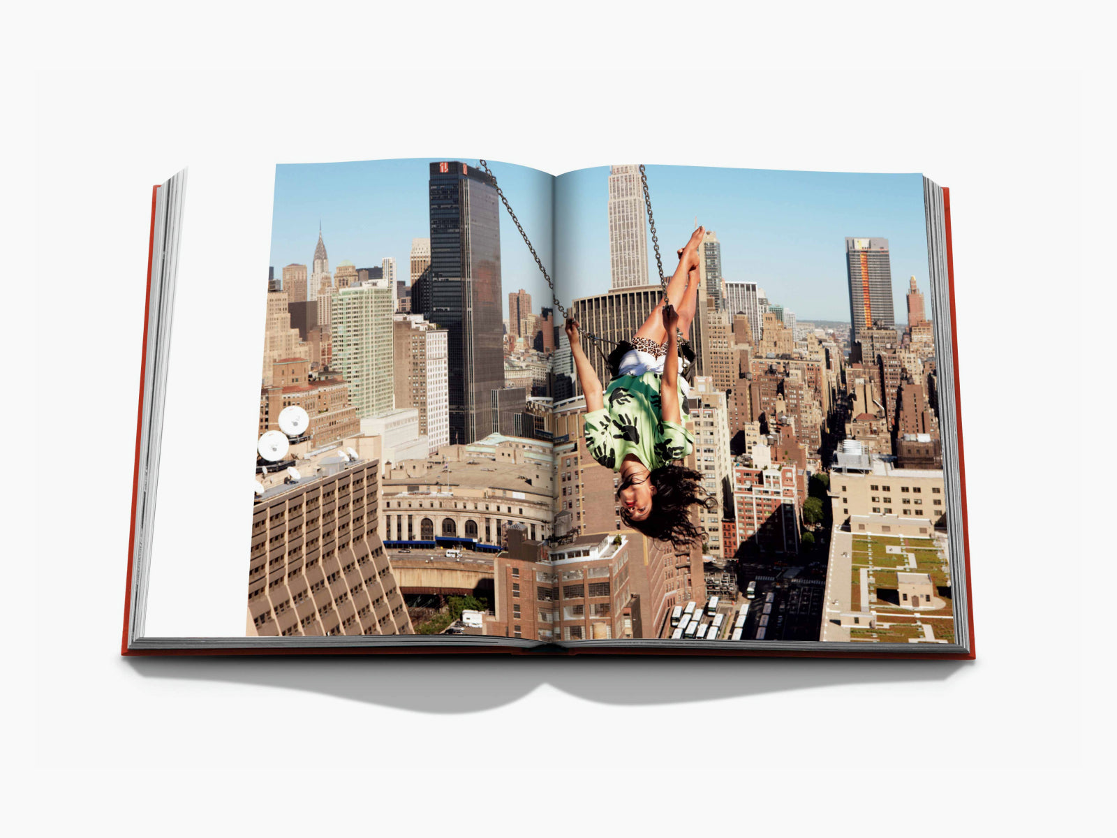 Two page spread featuring a woman hanging upside down above a Manhattan skyline across both pages