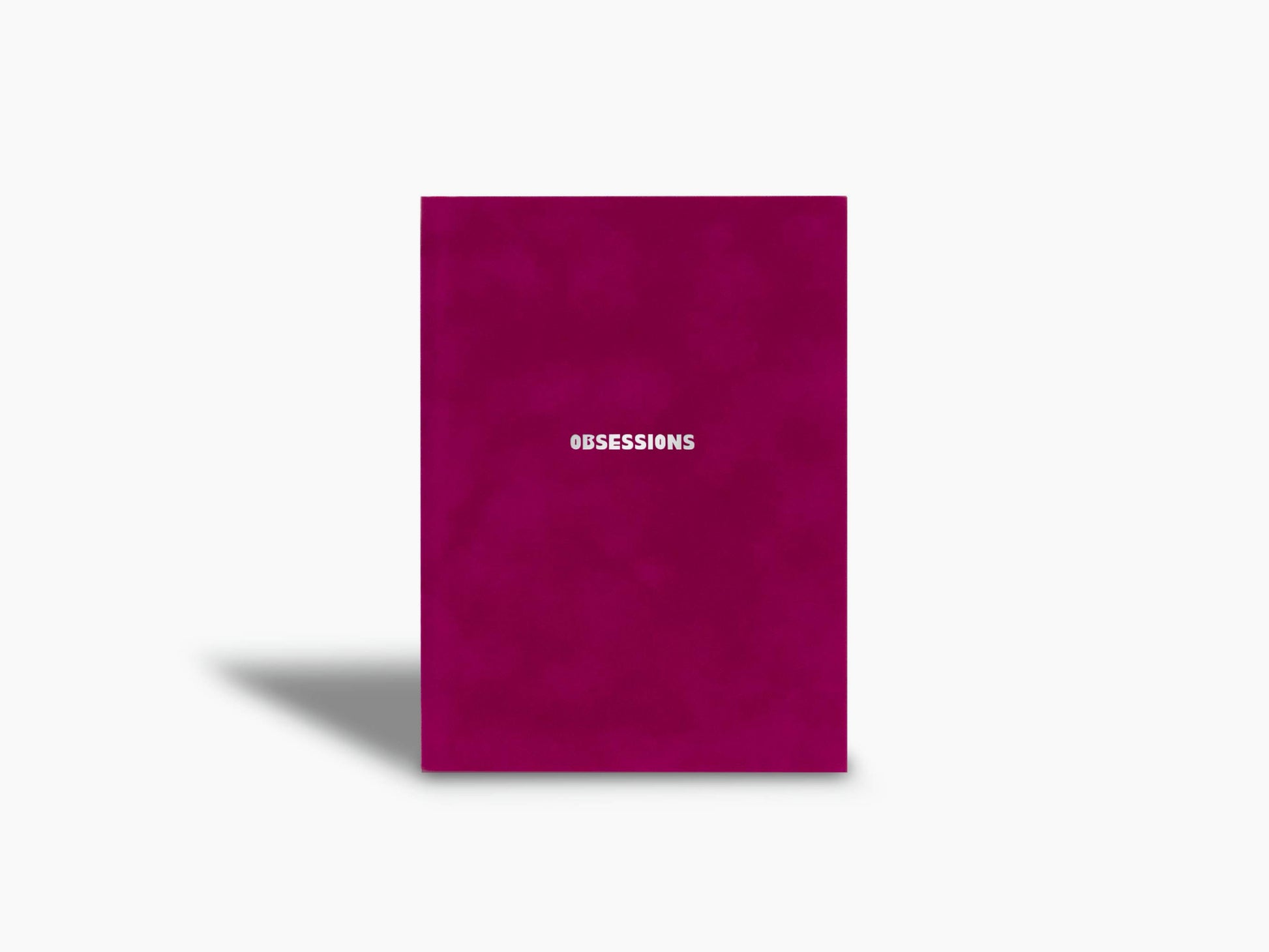 Magenta Assouline Obsessions notebook standing upright with the brand name at the bottom