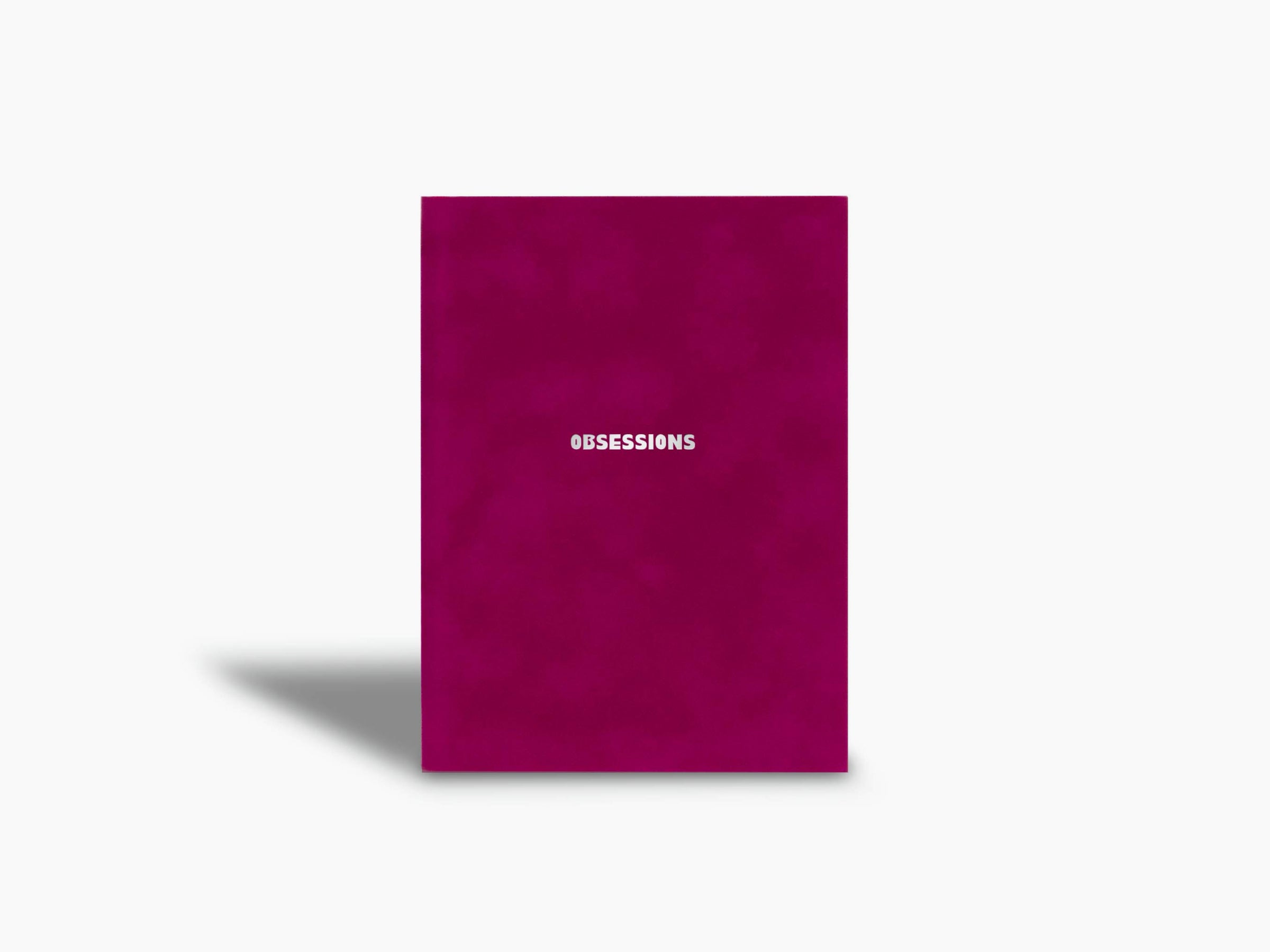 Magenta Assouline Obsessions notebook standing upright with the brand name at the bottom