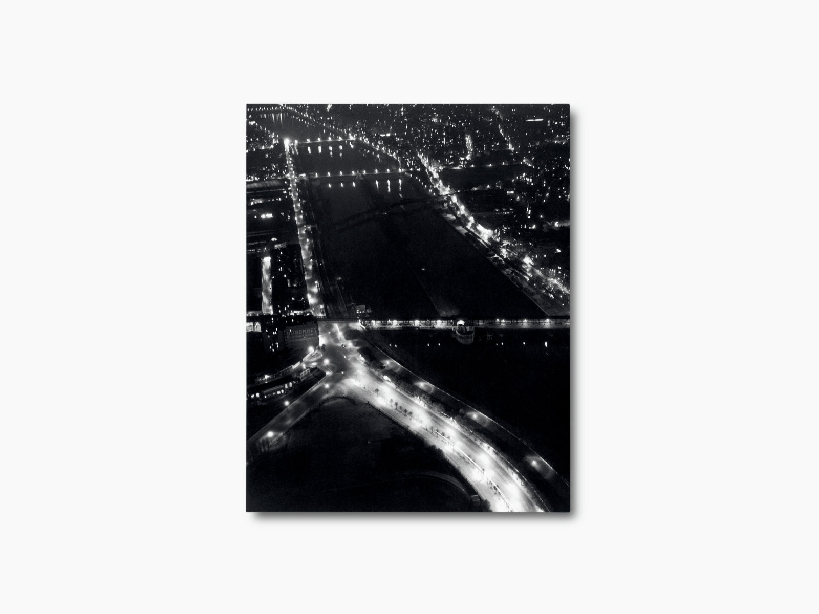 Black and white aerial night view of a city with glowing bridges and a winding river.