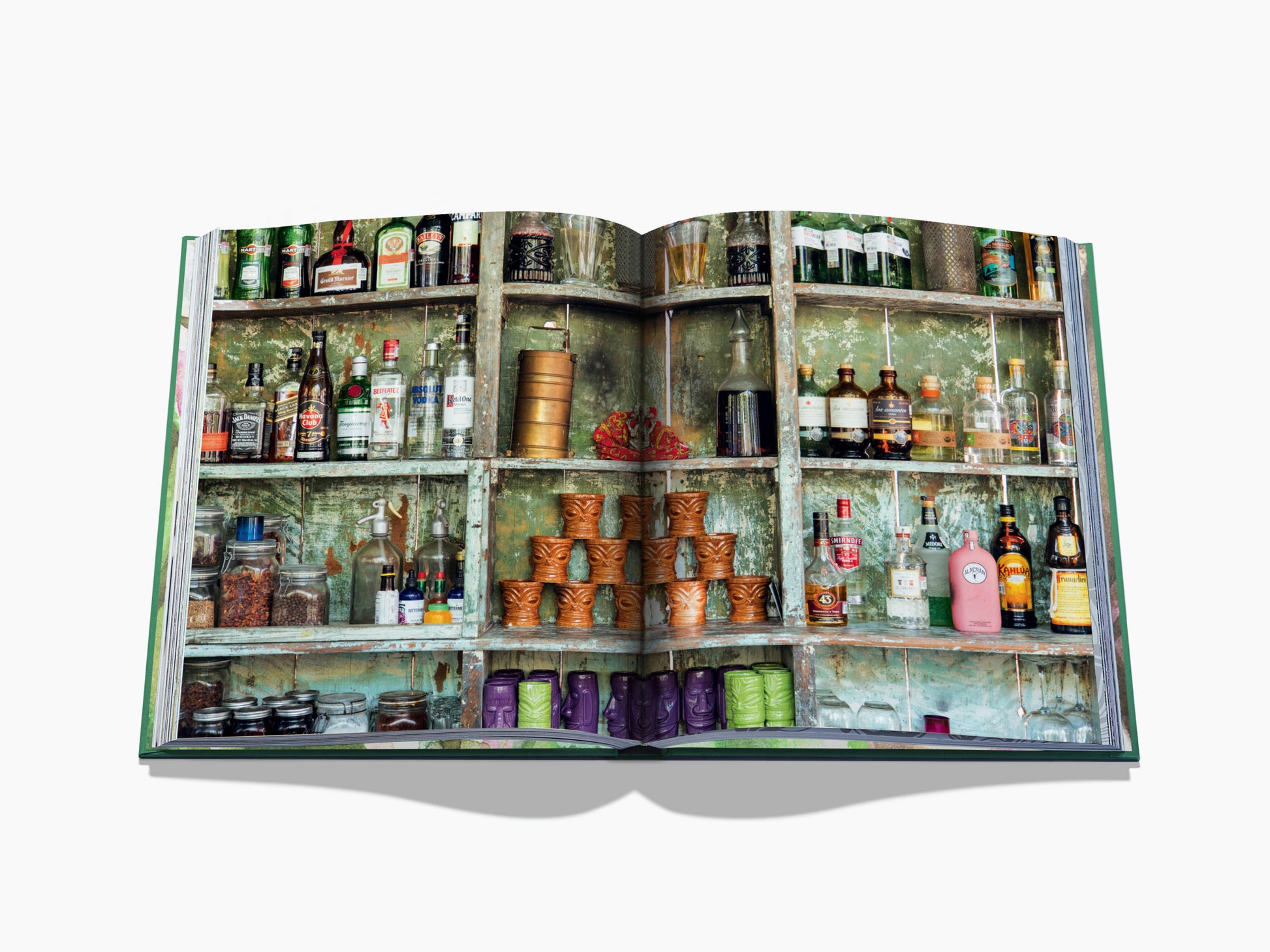 Spread image of a weathered green cabinet stocked with bottles and jars, creating a colorful rustic bar scene.