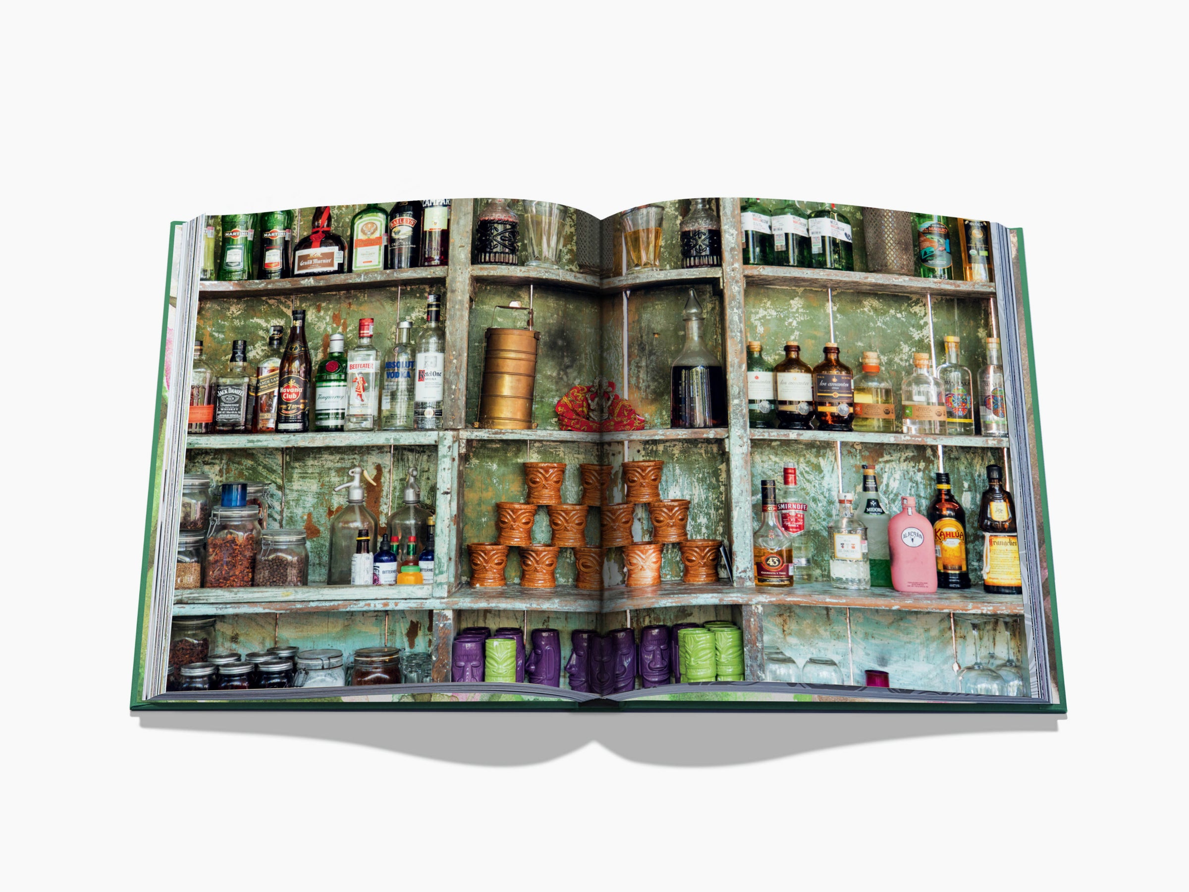 Spread image of a weathered green cabinet stocked with bottles and jars, creating a colorful rustic bar scene.
