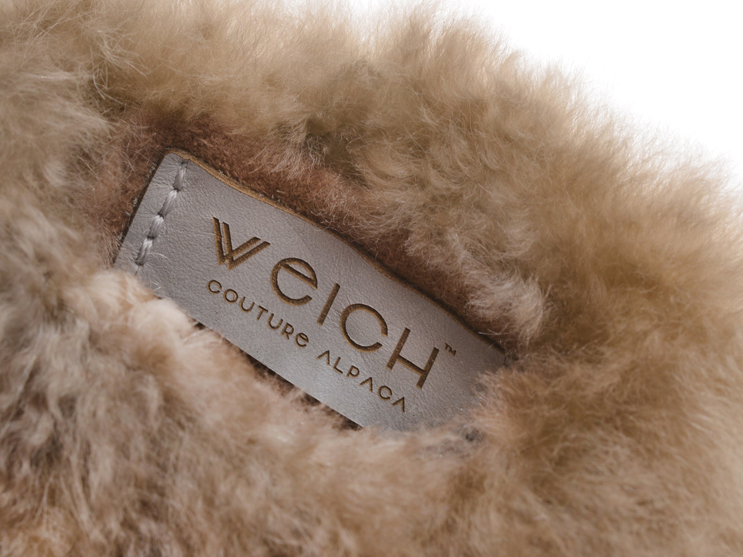 Close-up of CALMO hot-water bottle tag nestled in fluffy alpaca fur.