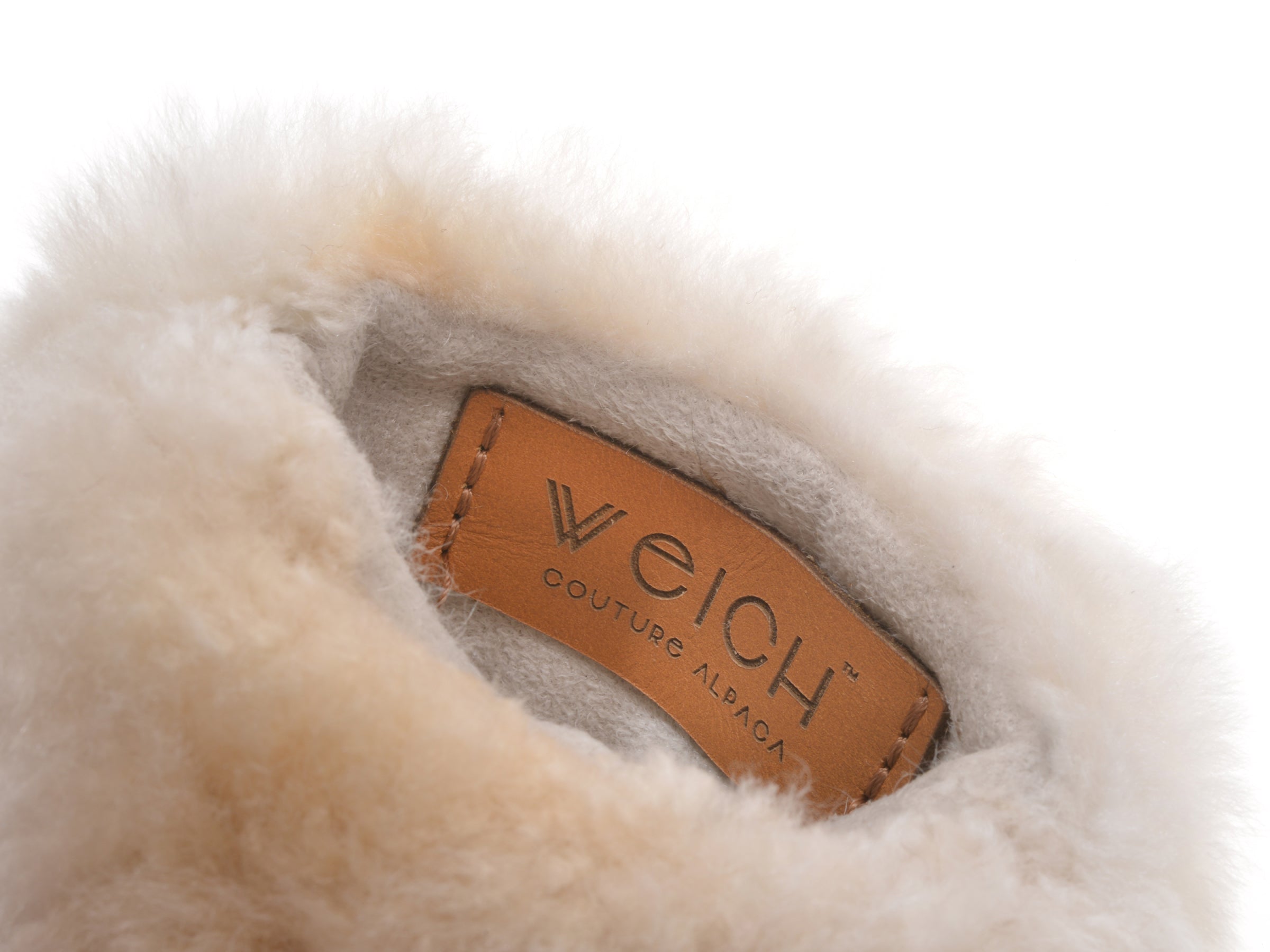 Inner view of plush cream alpaca lining with a tan leather label stitched inside.
