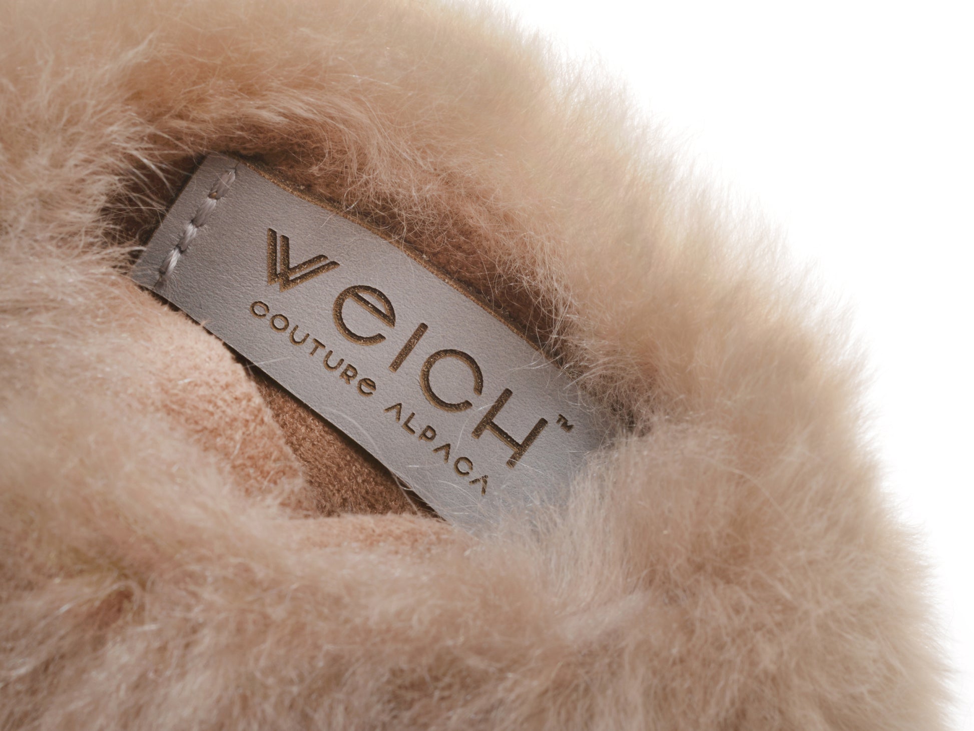 Close-up of beige alpaca fur with a gray leather tag reading Welch Couture Alpaca.