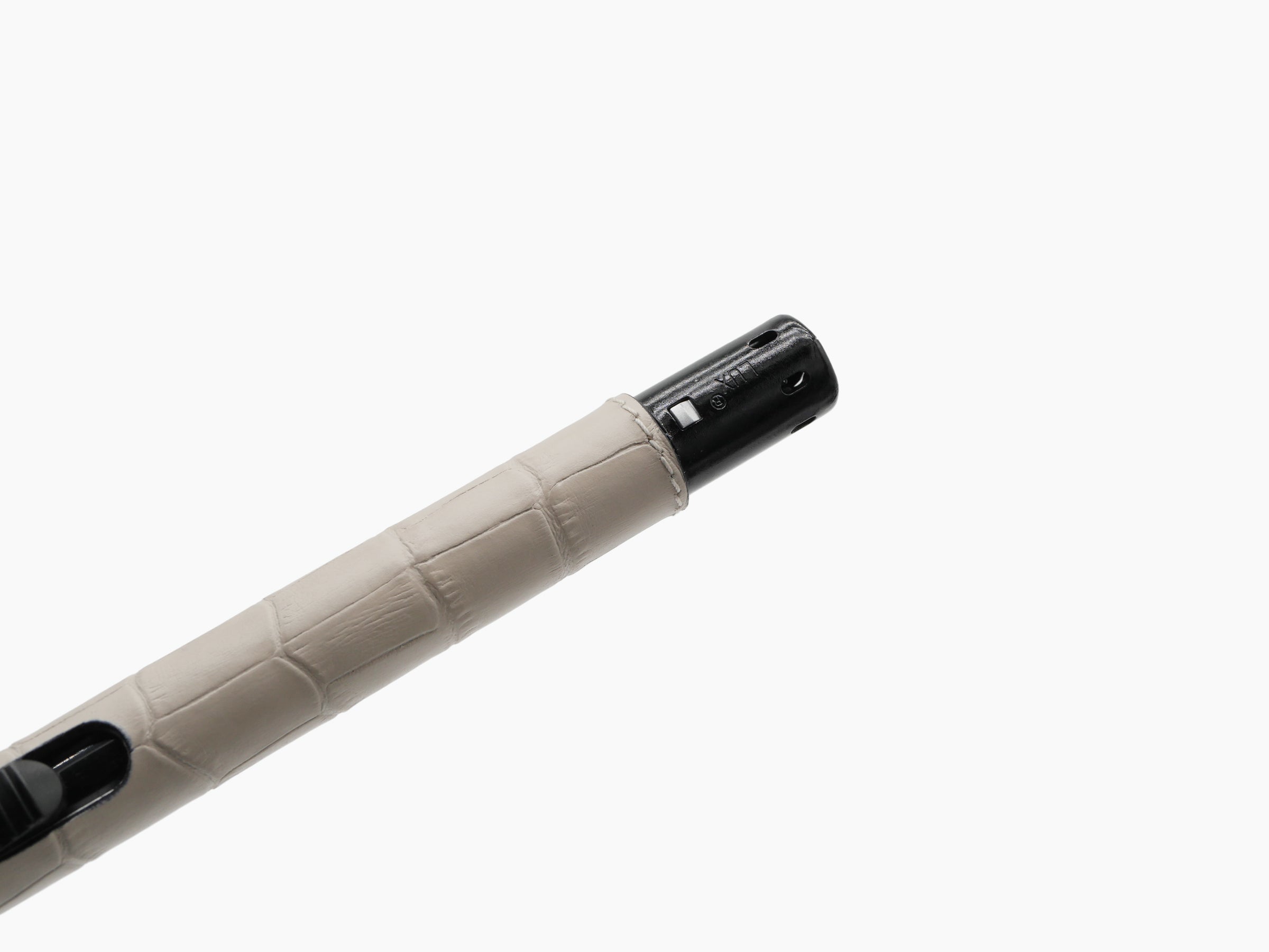 Close up of a sleek metal lighter with a beige leather wrapped shaft.