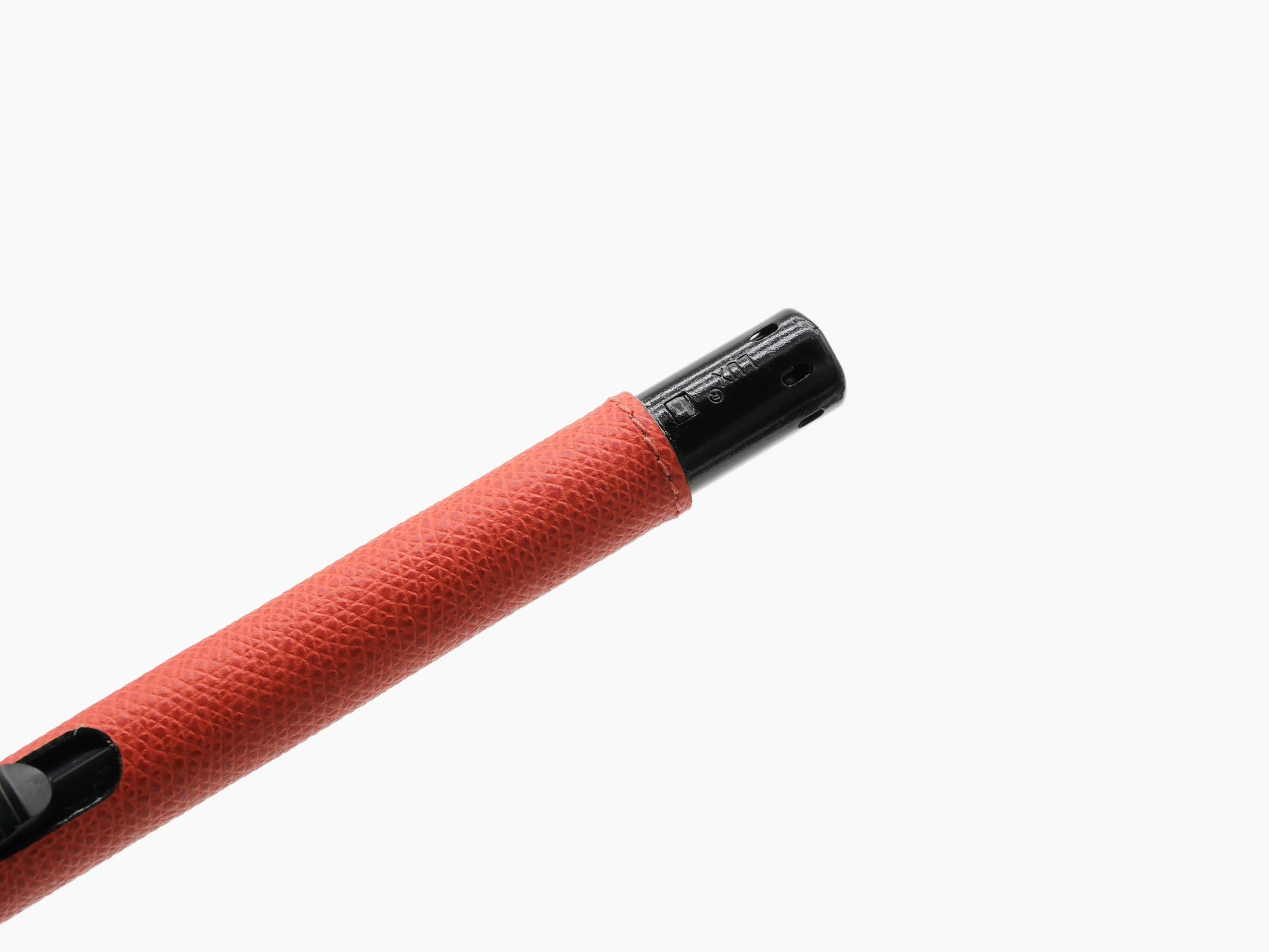 Close-up of red leather wrapped lighter showing black metal nozzle at the tip