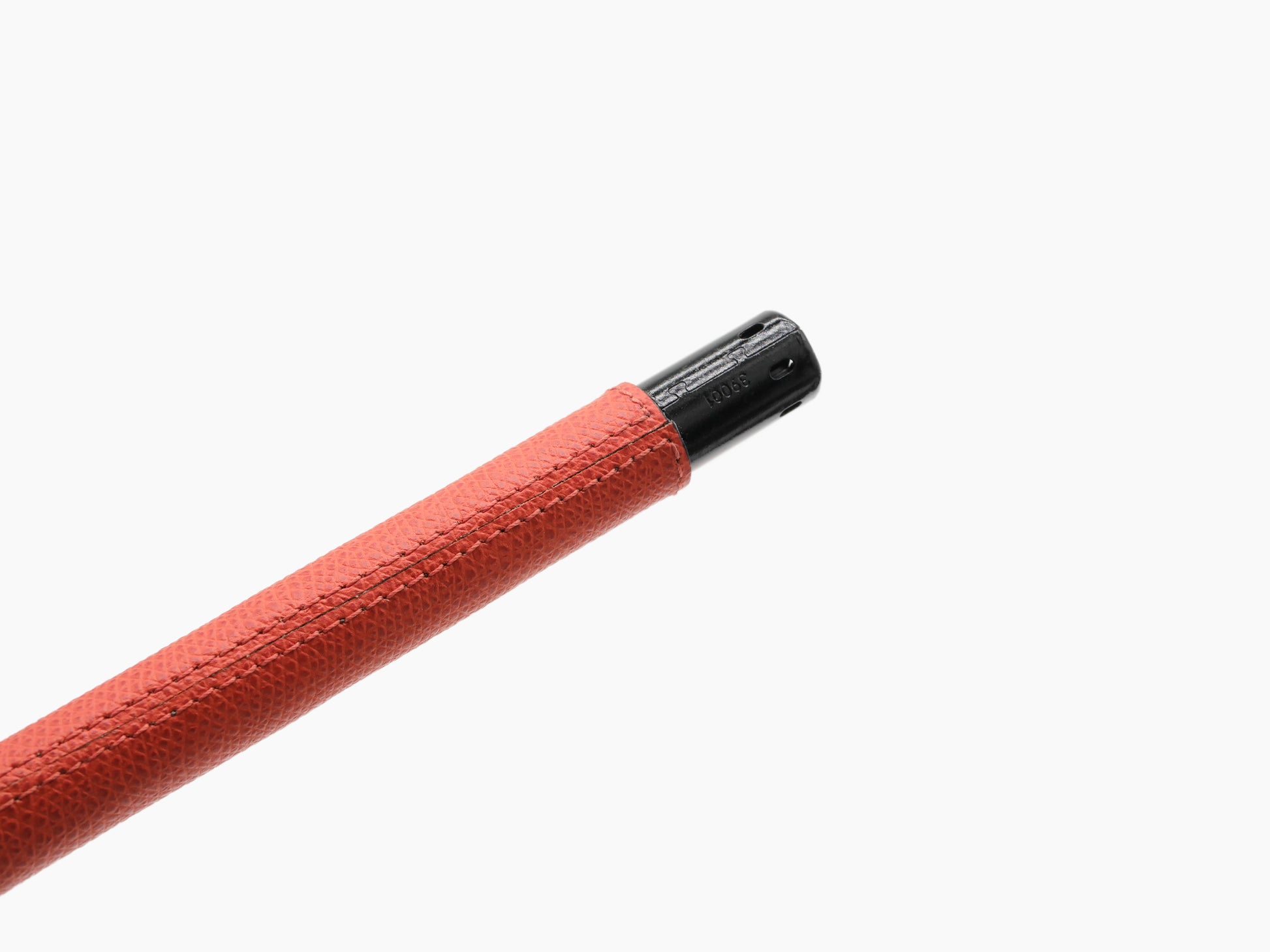 Angled view of the red leather wrapped lighter with a black metal cap at the end