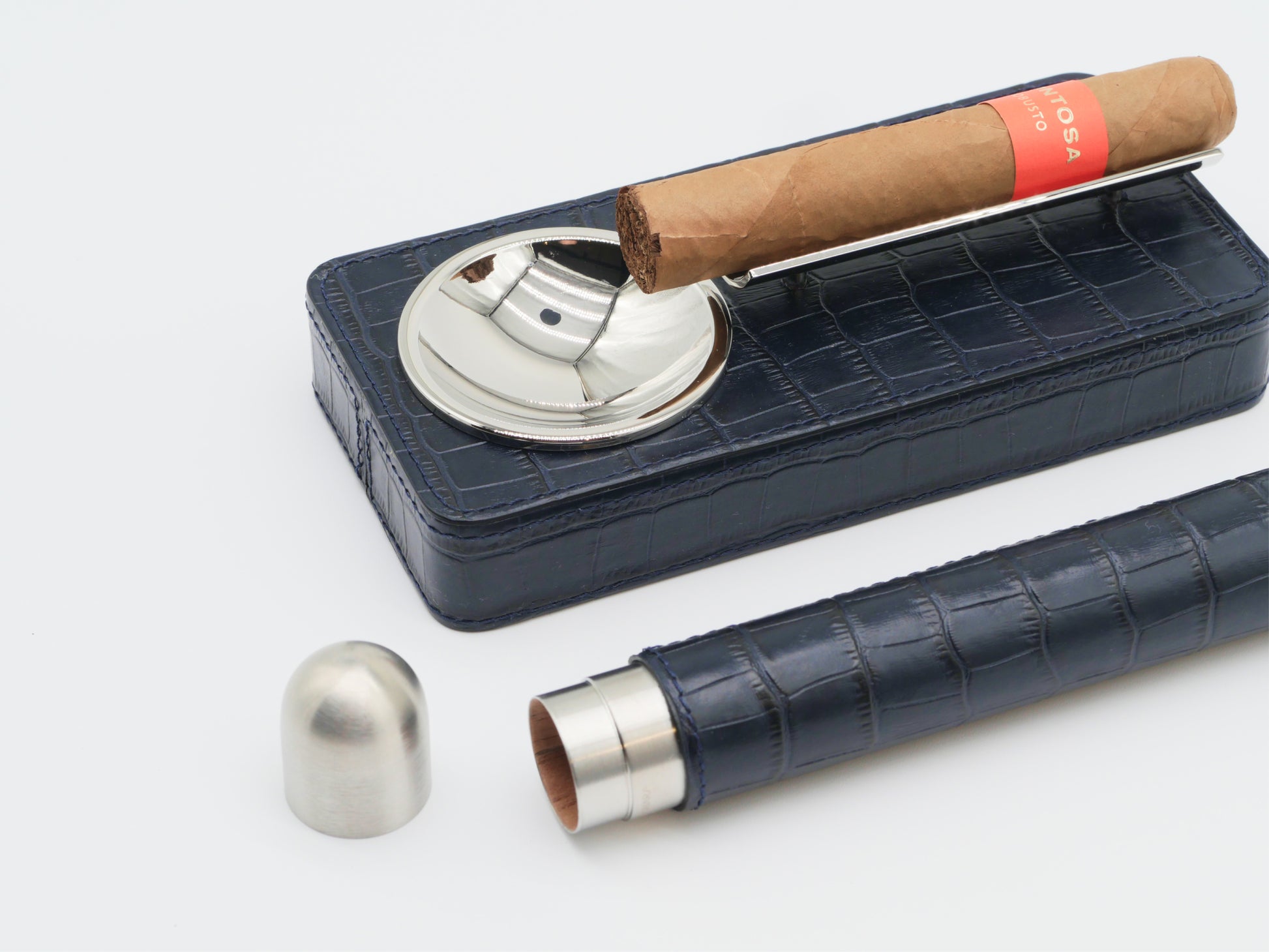 Royal Blue leather cigar gift set with a chrome ashtray and holder, a brown cigar resting on a metal rod above the case