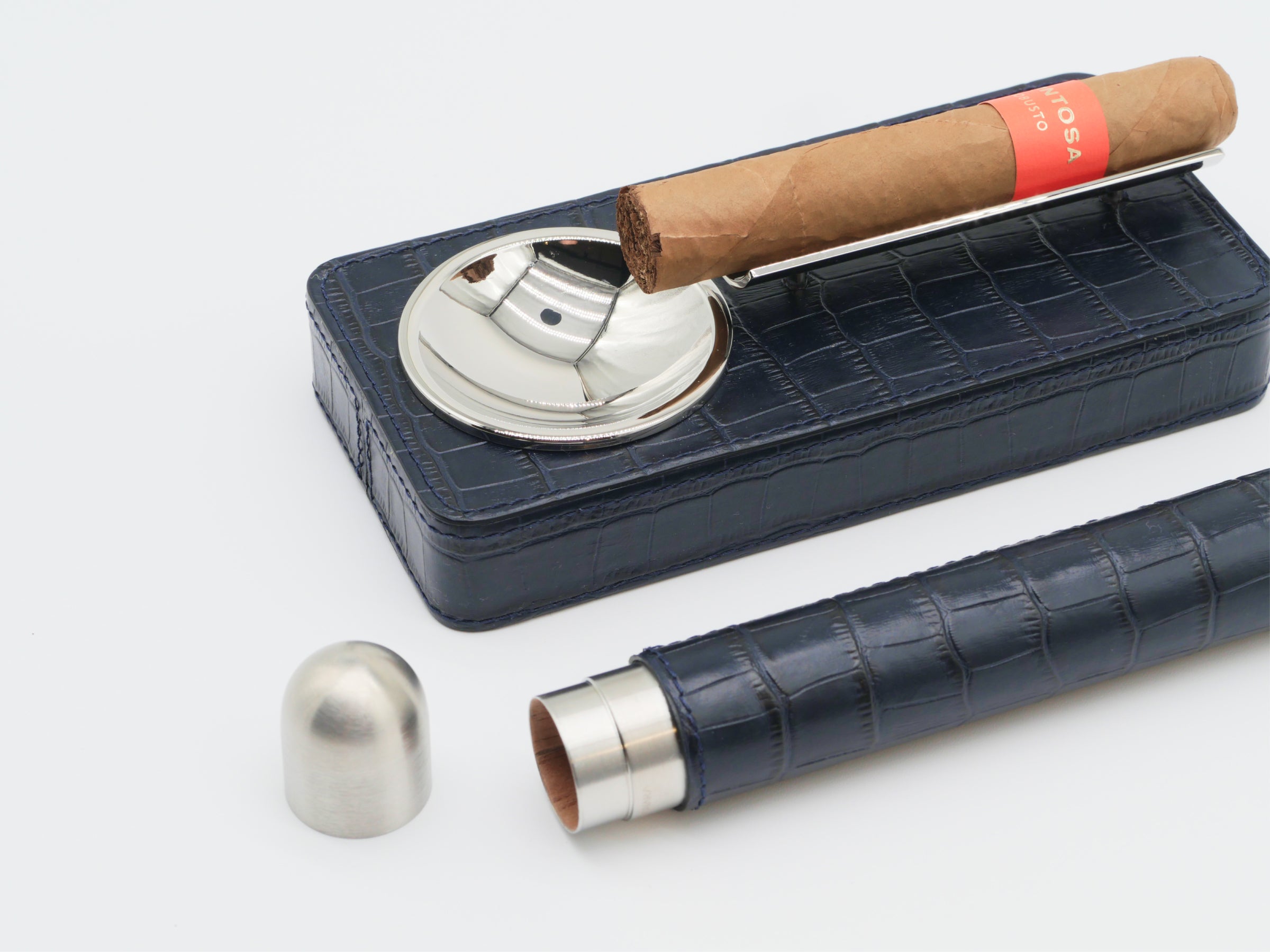 Royal Blue leather cigar gift set with a chrome ashtray and holder, a brown cigar resting on a metal rod above the case