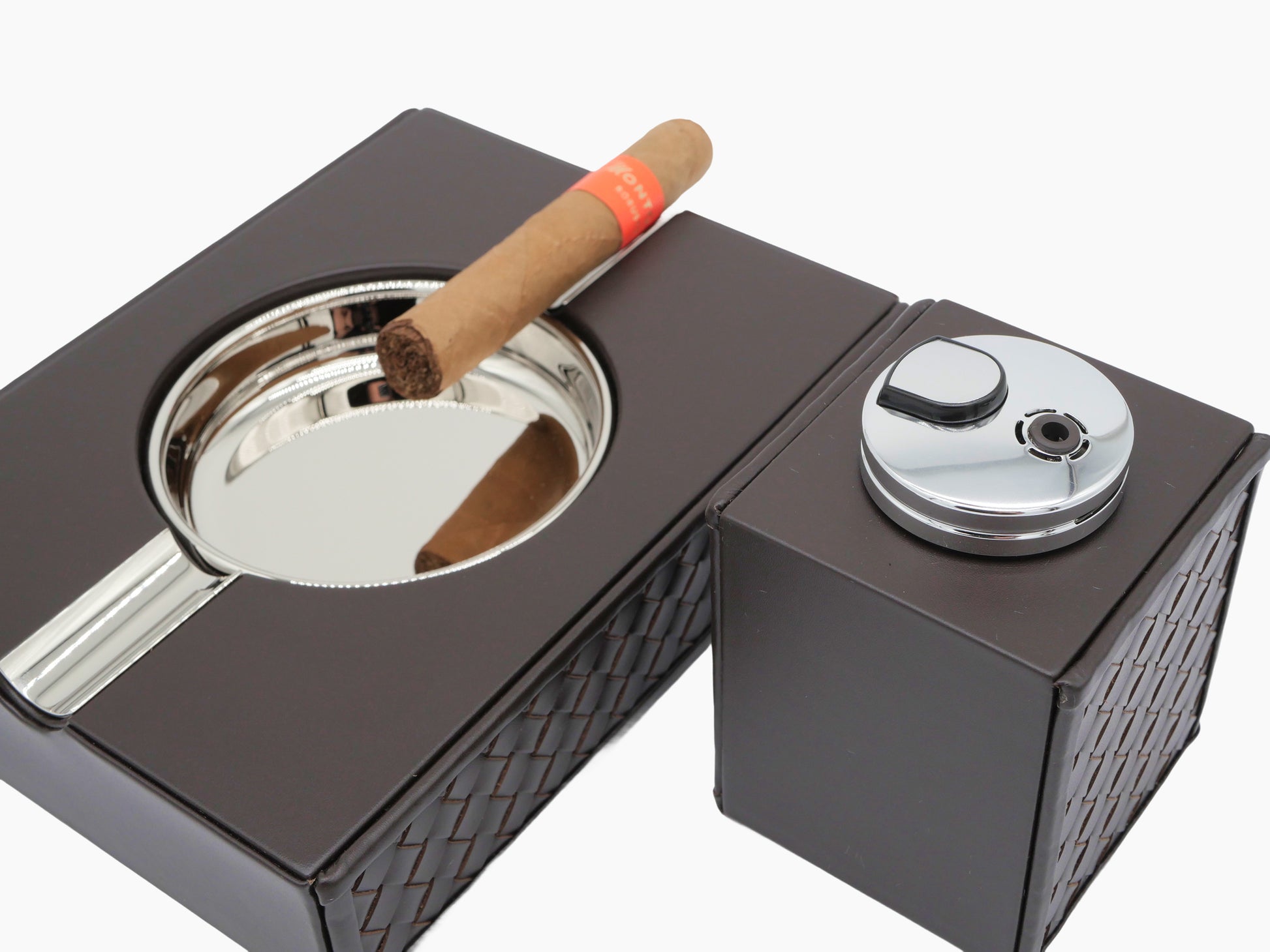 Riviere handwoven leather cigar accessories set with a chrome ashtray and Nereo table lighter on a dark display case