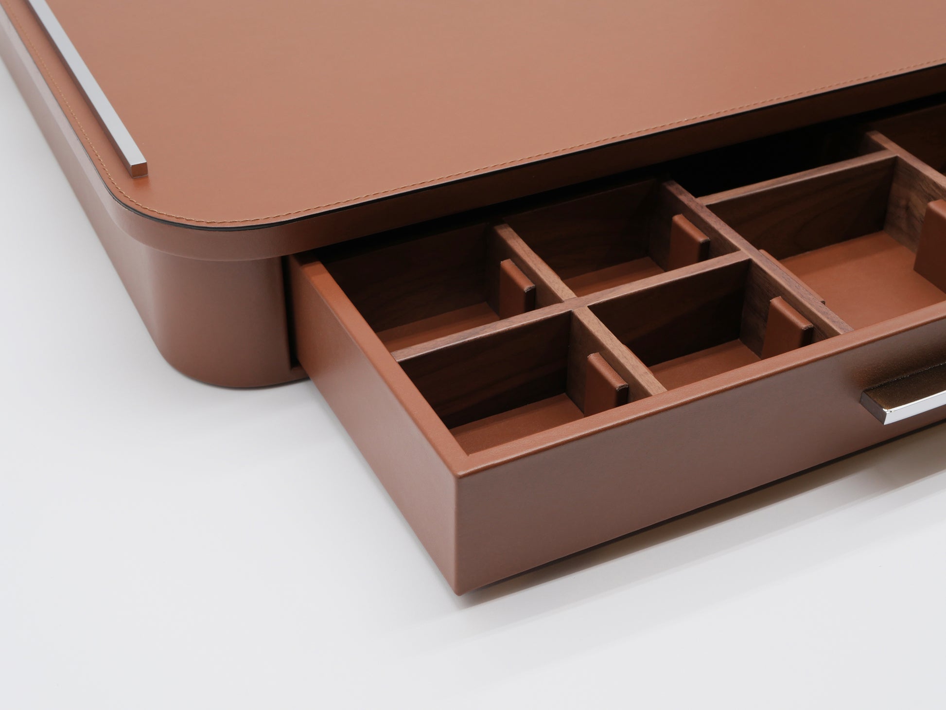 Open drawer of a leather wrapped coffee organizer with a walnut interior and divided compartments for spoons, sugar, tea bags, and capsules