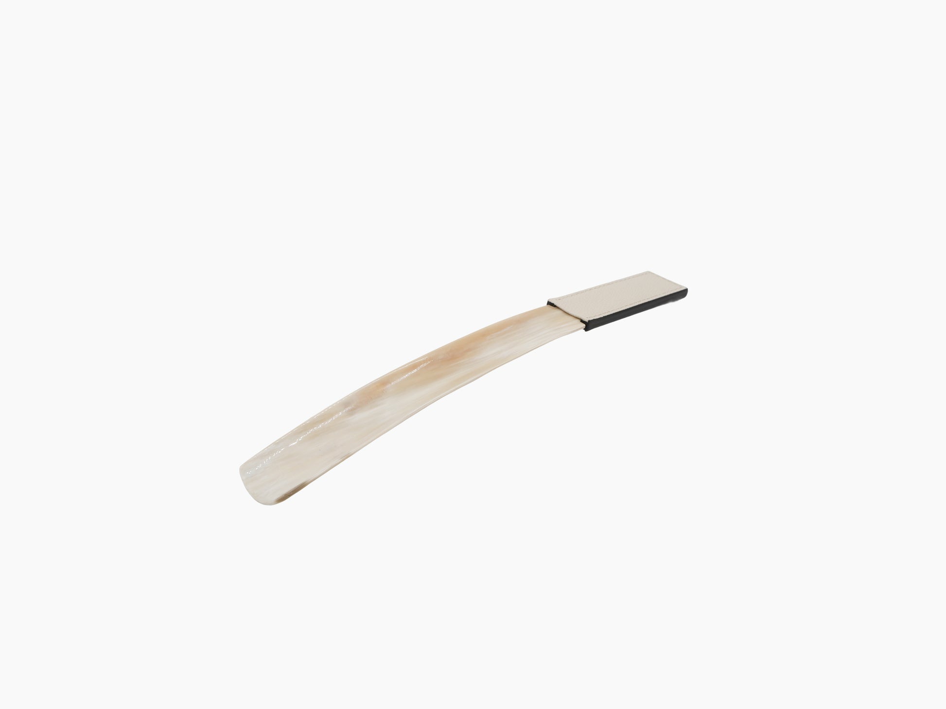 Curved buffalo horn shoehorn with beige leather handle on white background