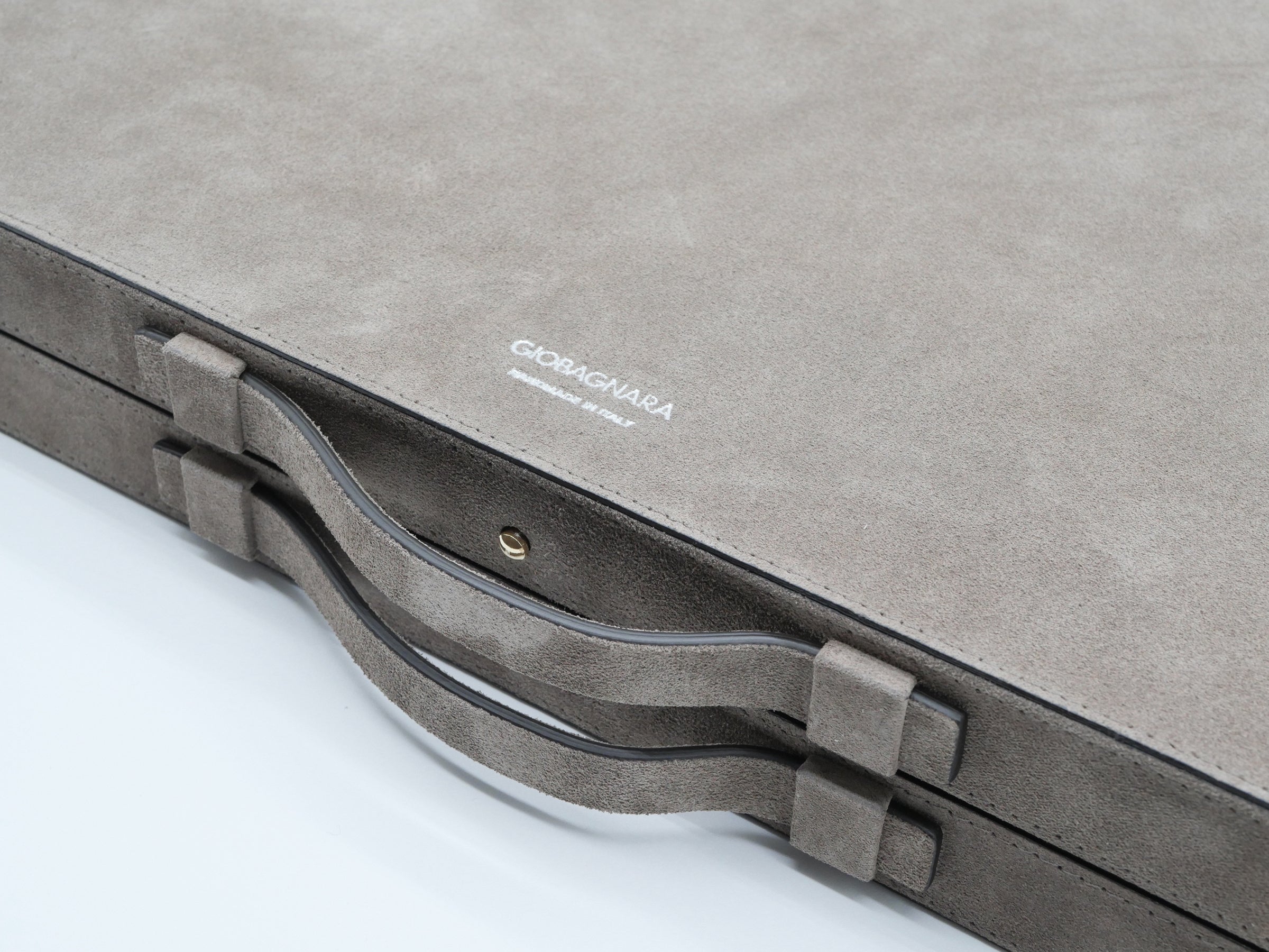 Close-up of the Bond backgammon case in taupe suede with a white Giobagnara logo and curved handles