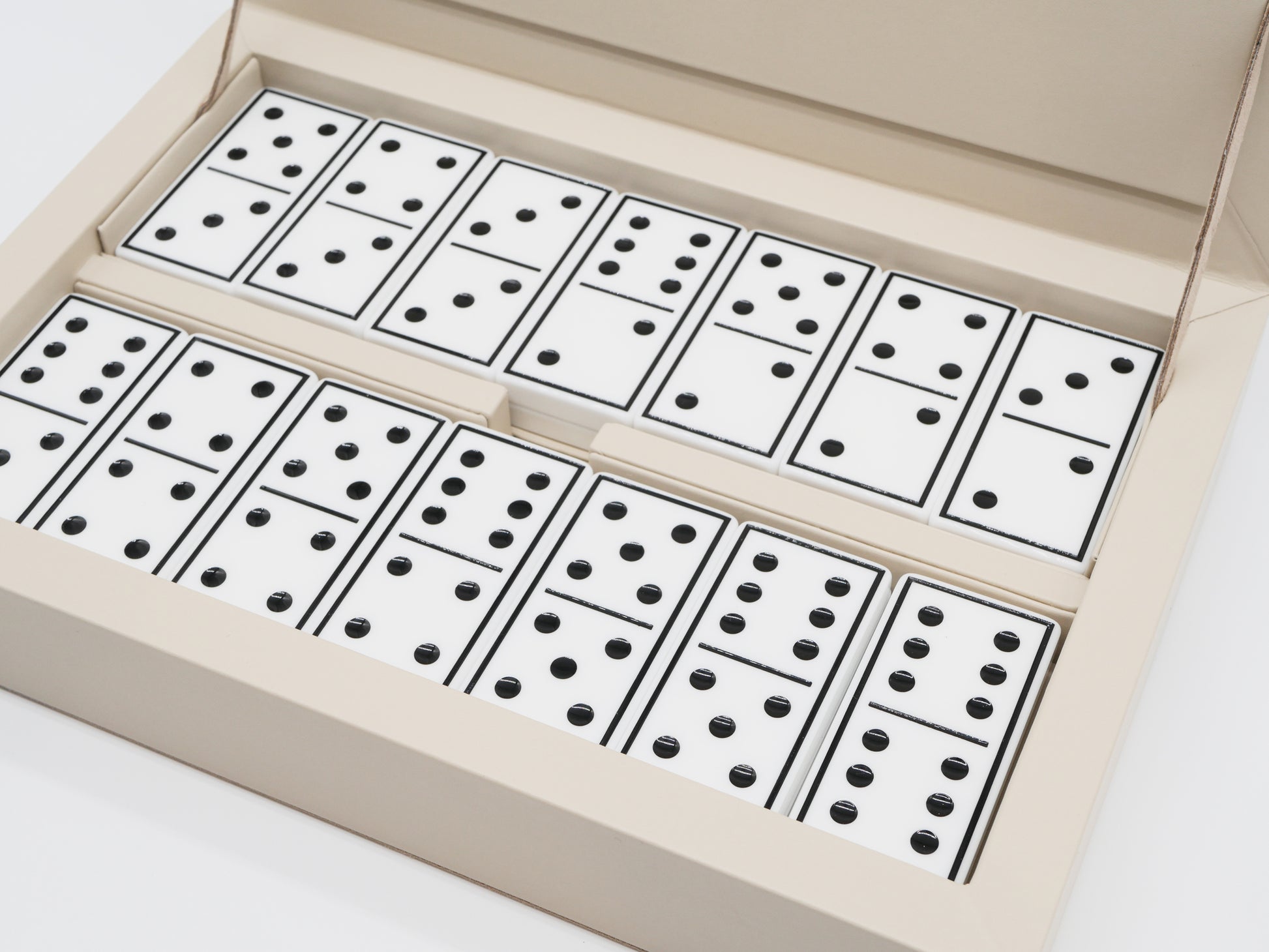Close up of beige Eva Domino Game Set showing white domino tiles with black pips arranged in rows inside the box