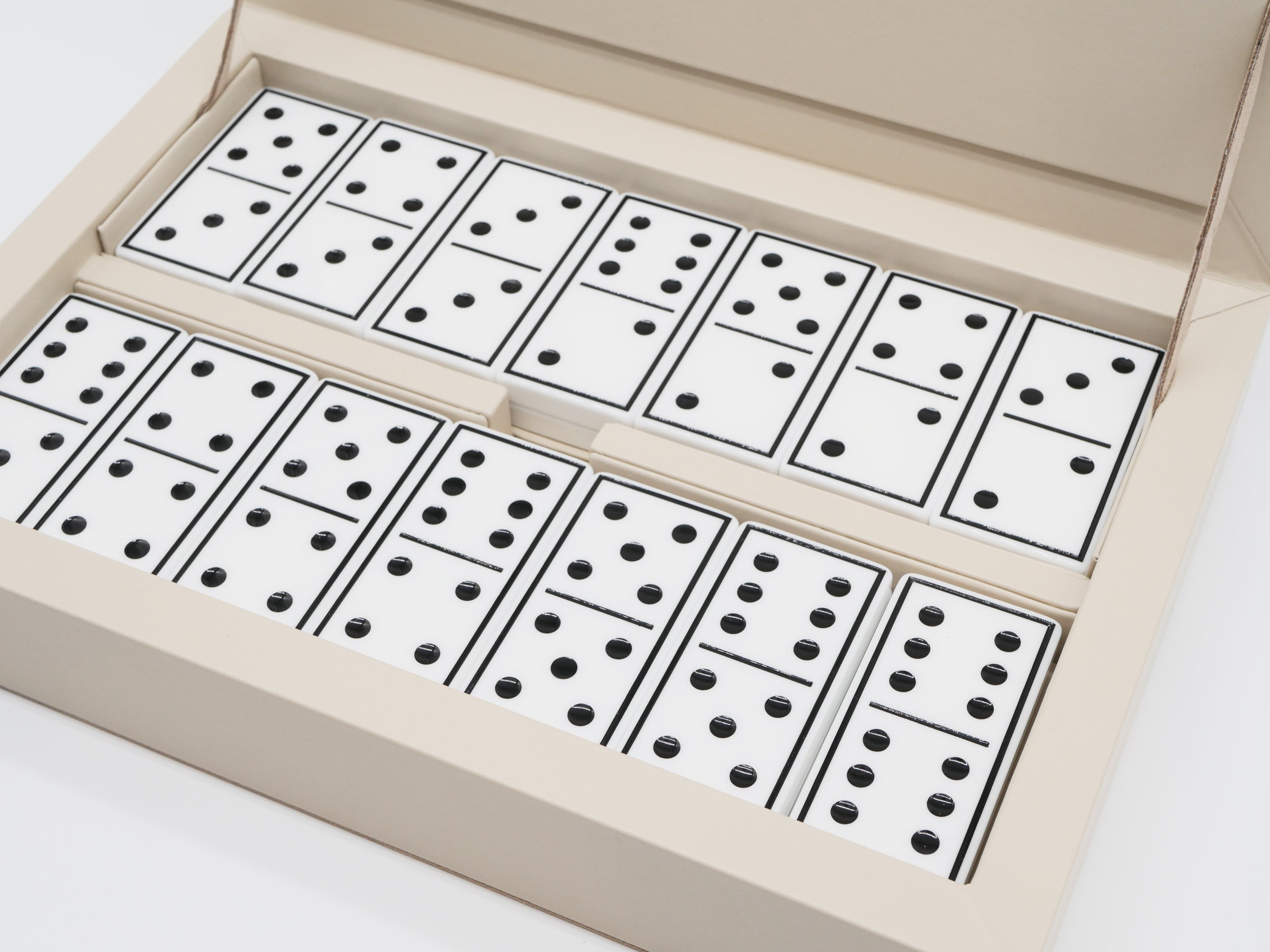 Close up of beige Eva Domino Game Set showing white domino tiles with black pips arranged in rows inside the box