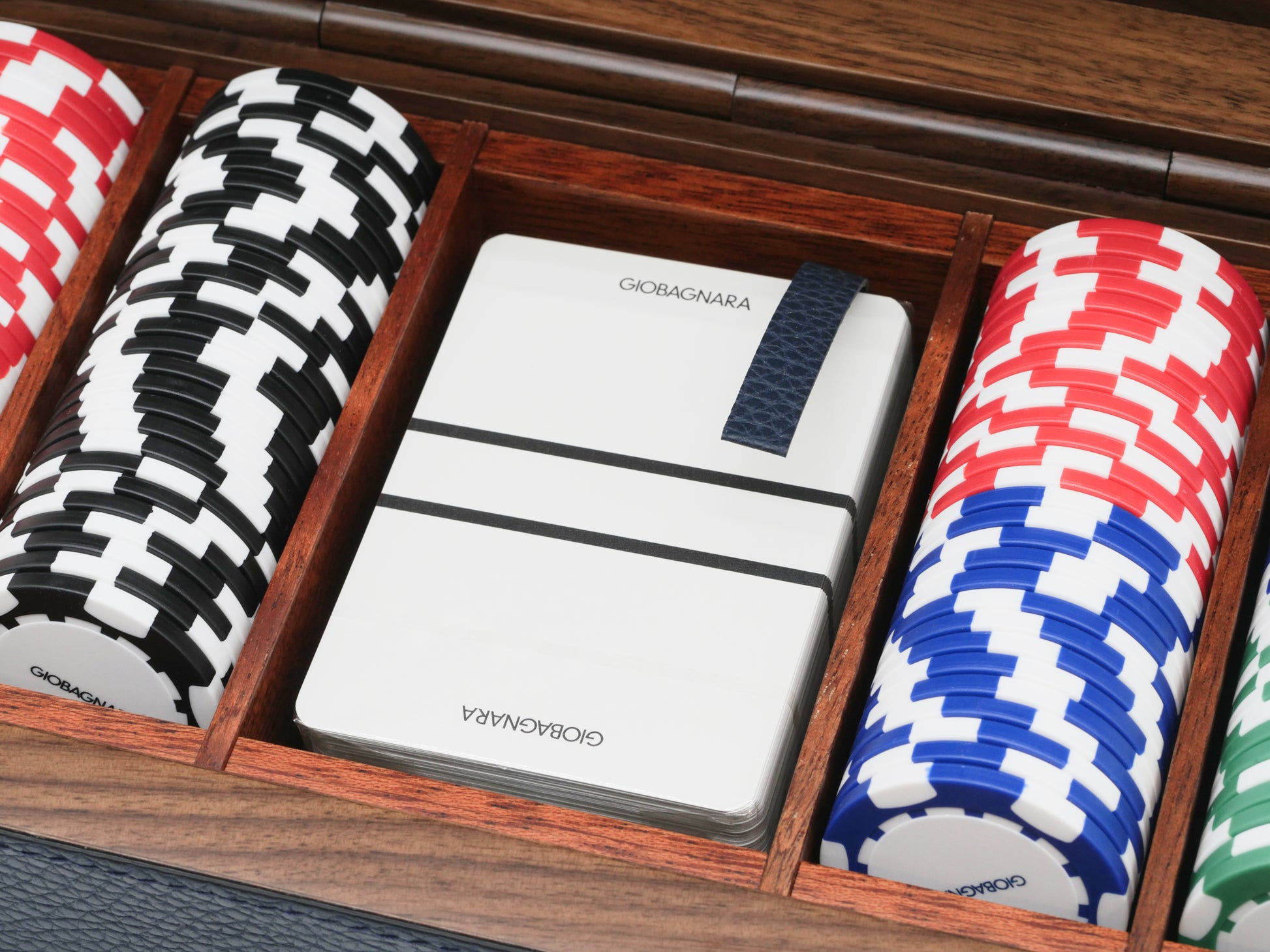 Premium playing cards secured by a blue leather strap inside a walnut mahogany case with poker chips nearby