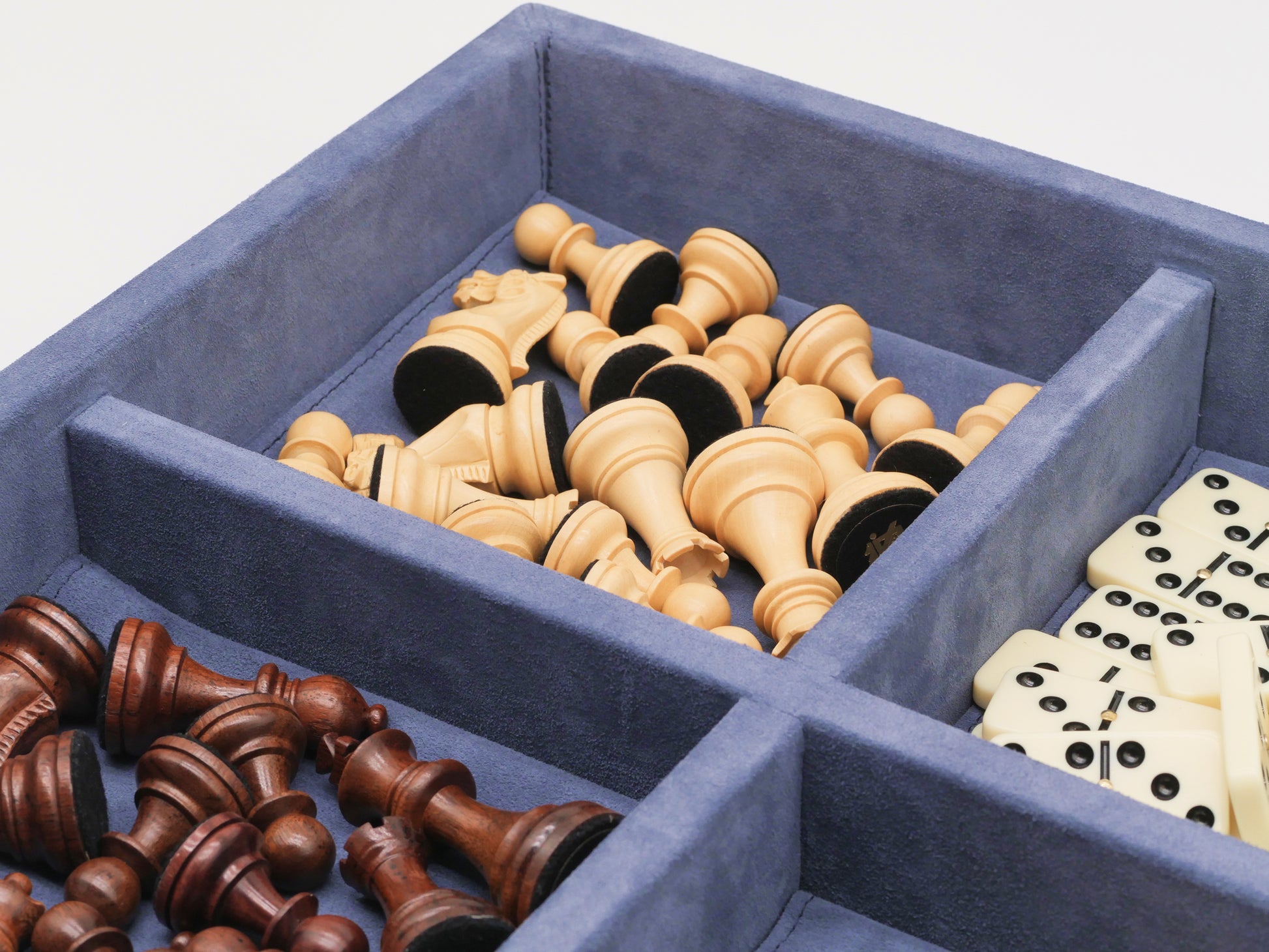 Blue suede case shows round wooden checkers in the foreground with chess pieces and dominoes visible in the background.