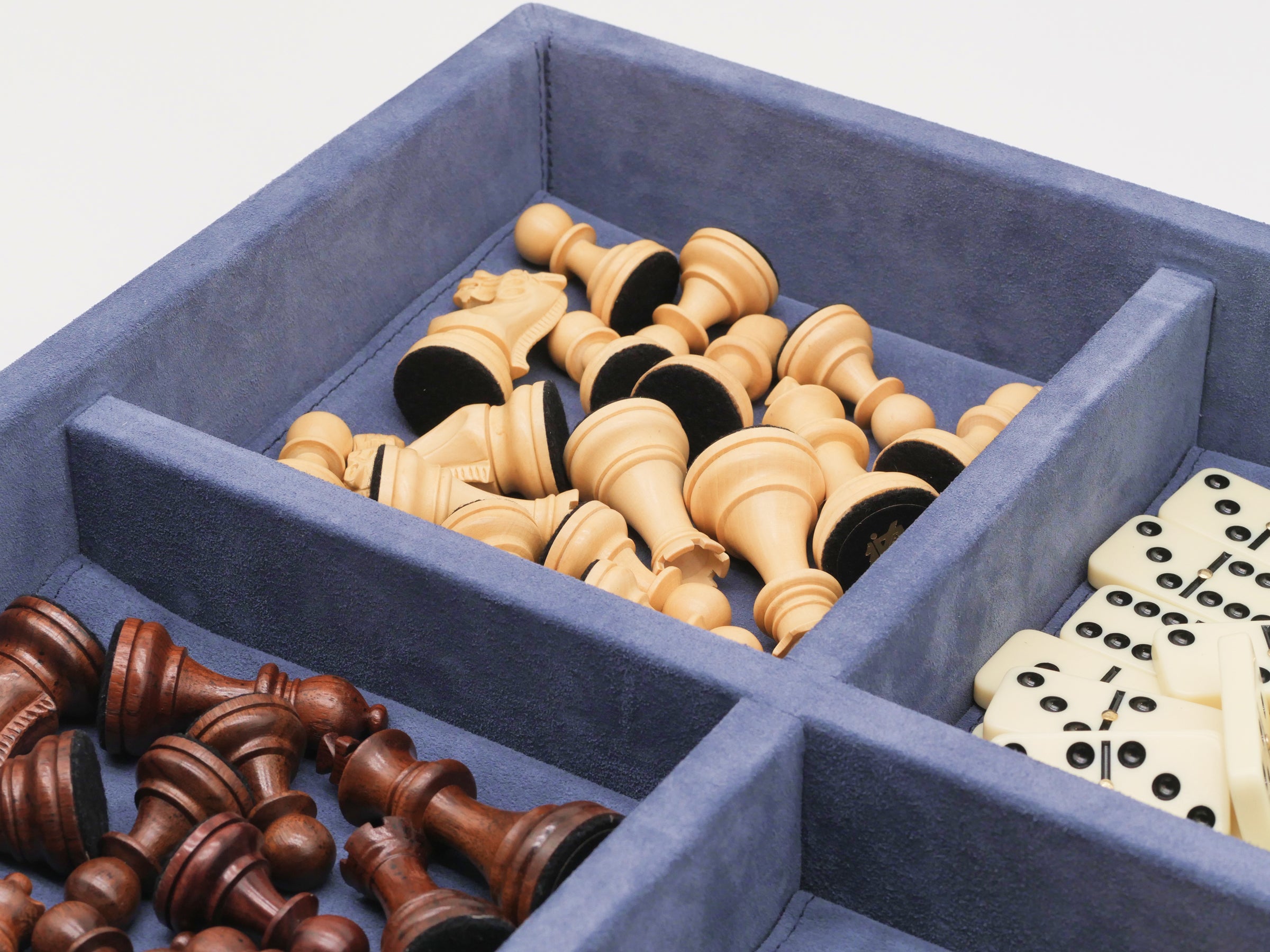 Blue suede case shows round wooden checkers in the foreground with chess pieces and dominoes visible in the background.