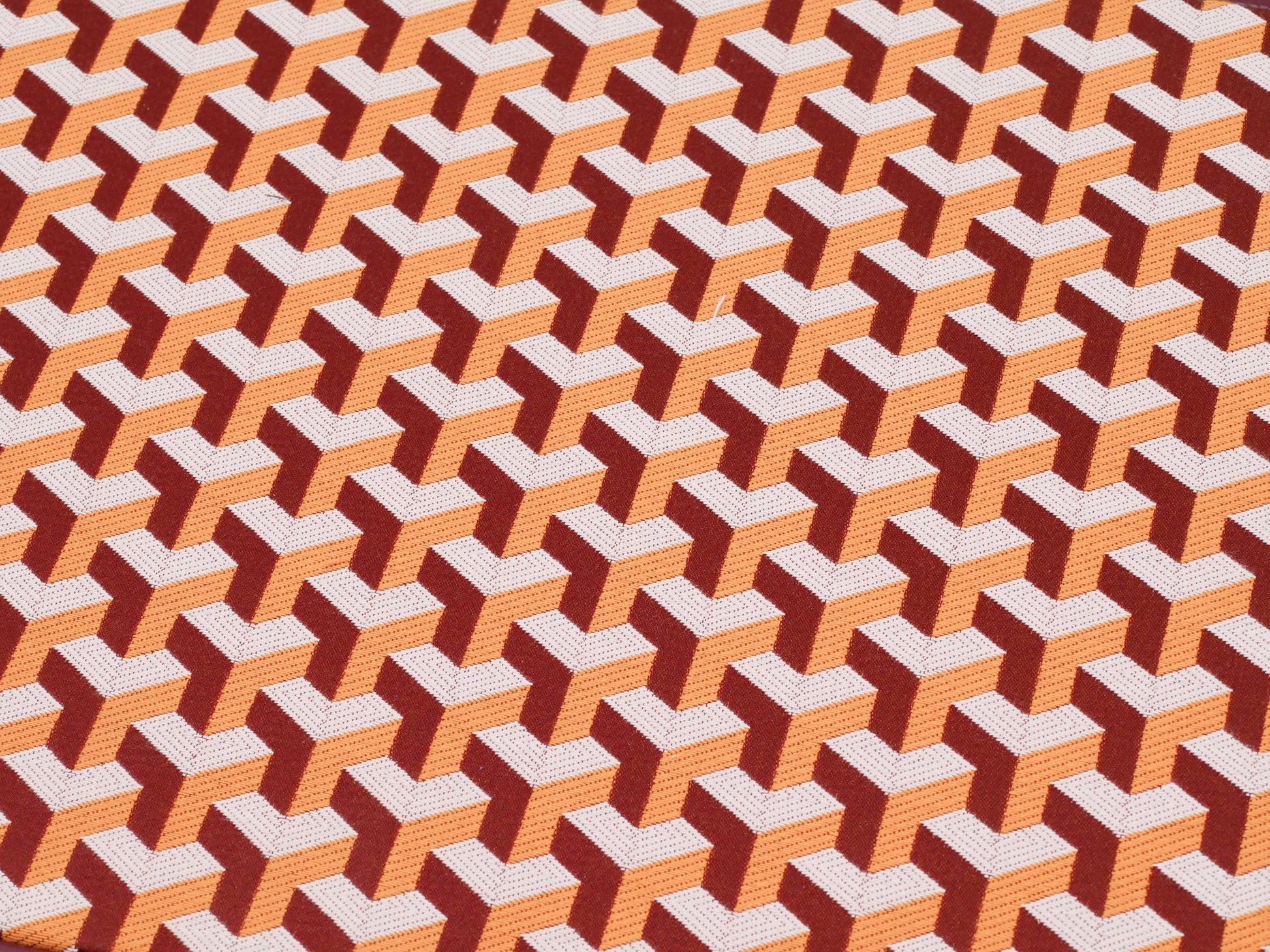 Close-up of backgammon board surface showing a repeating orange and brown geometric cube pattern