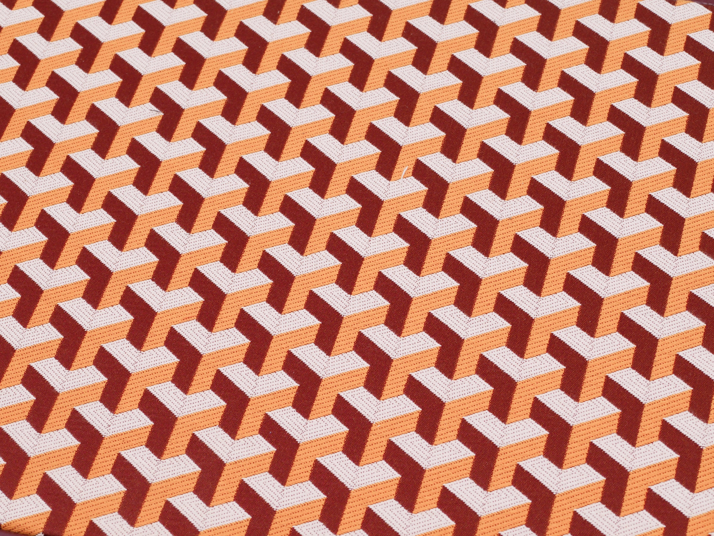 Close-up of backgammon board surface showing a repeating orange and brown geometric cube pattern