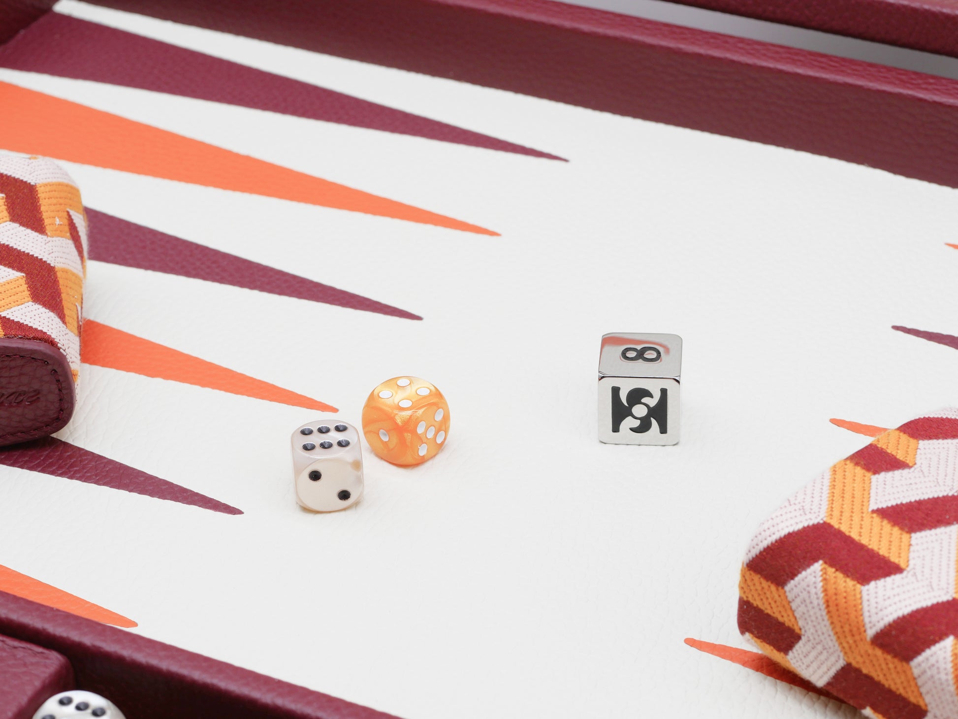 Close-up of backgammon play with orange patterned dice cups and scattered dice on a white and orange board