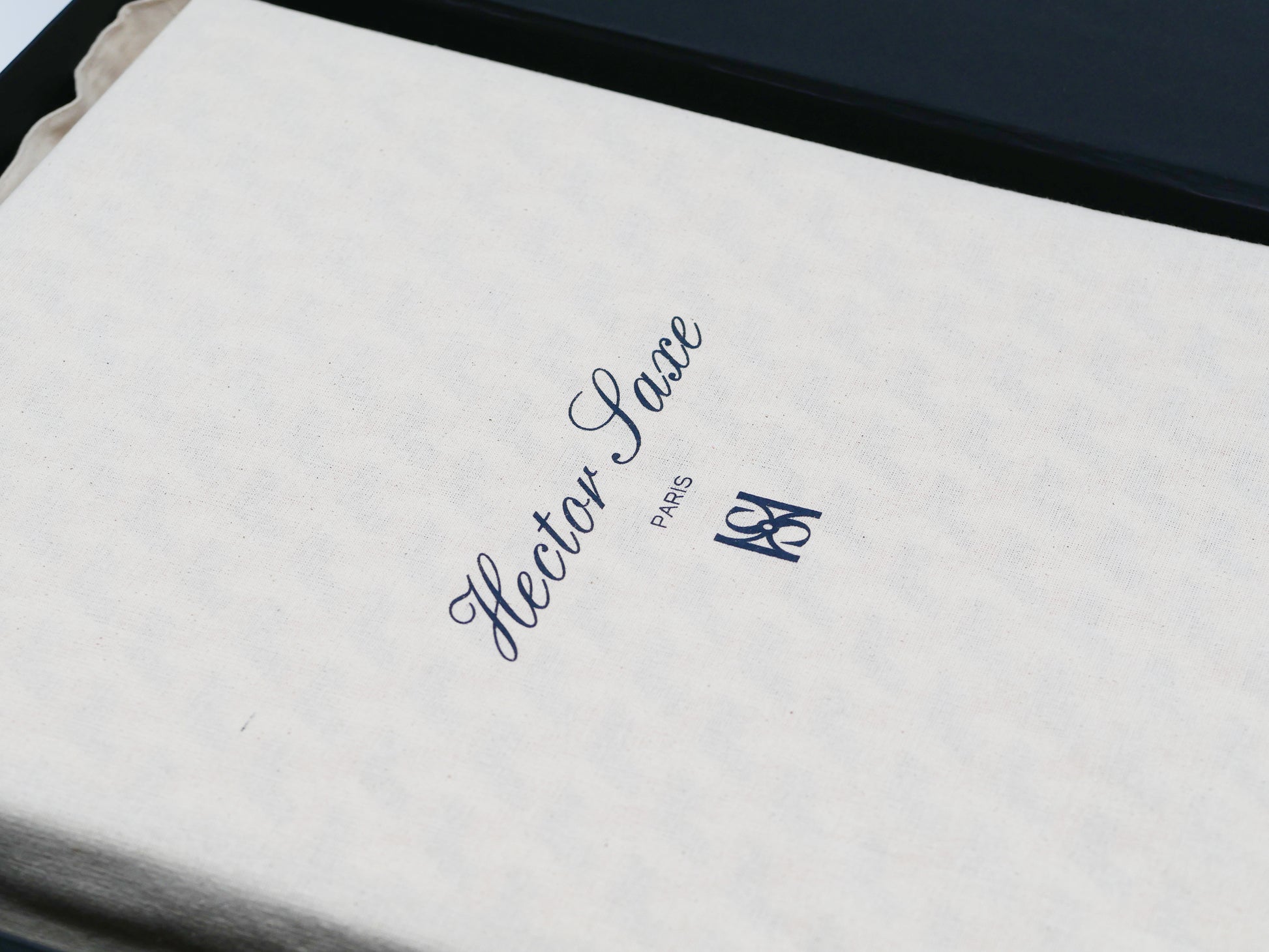 White protective pouch with blue cursive logo and Paris text beside a dark case