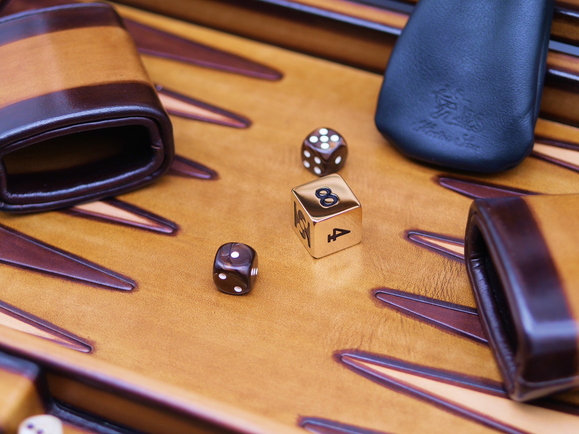 Close-up of patinable cognac backgammon board showing dice and leather pieces on a warm wooden surface.
