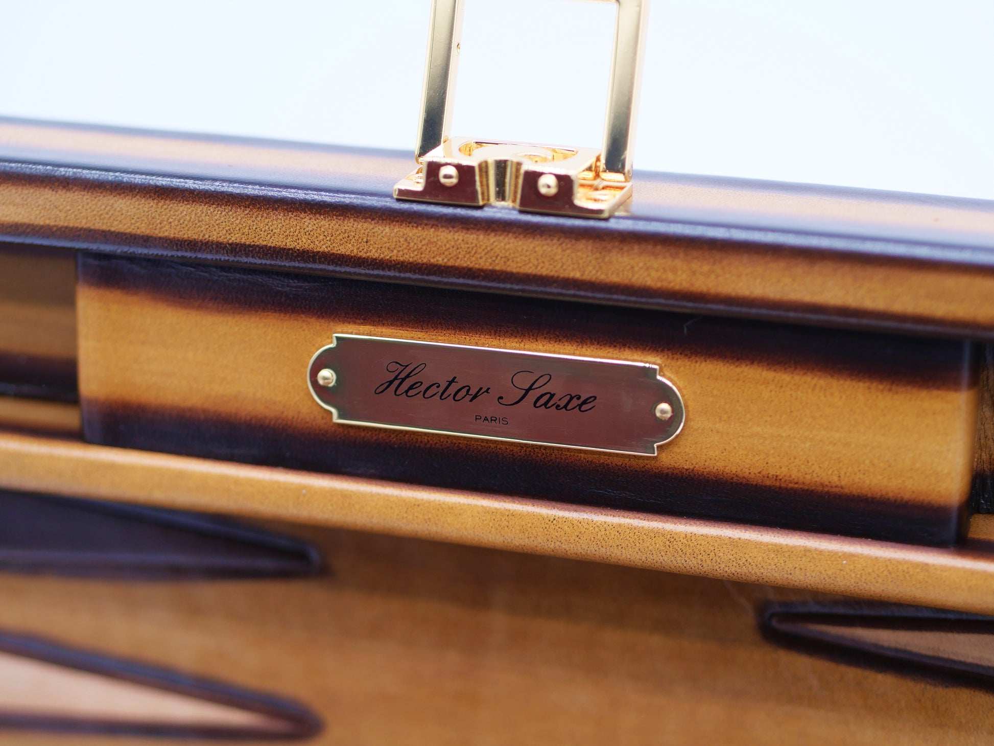 Close-up of a patinable cognac leather backgammon case with a metal plaque reading Hector Saxe Paris
