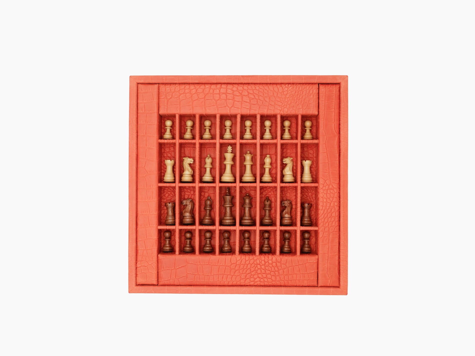 Open coral red leather chess case with grid compartments filled with light and dark wooden chess pieces