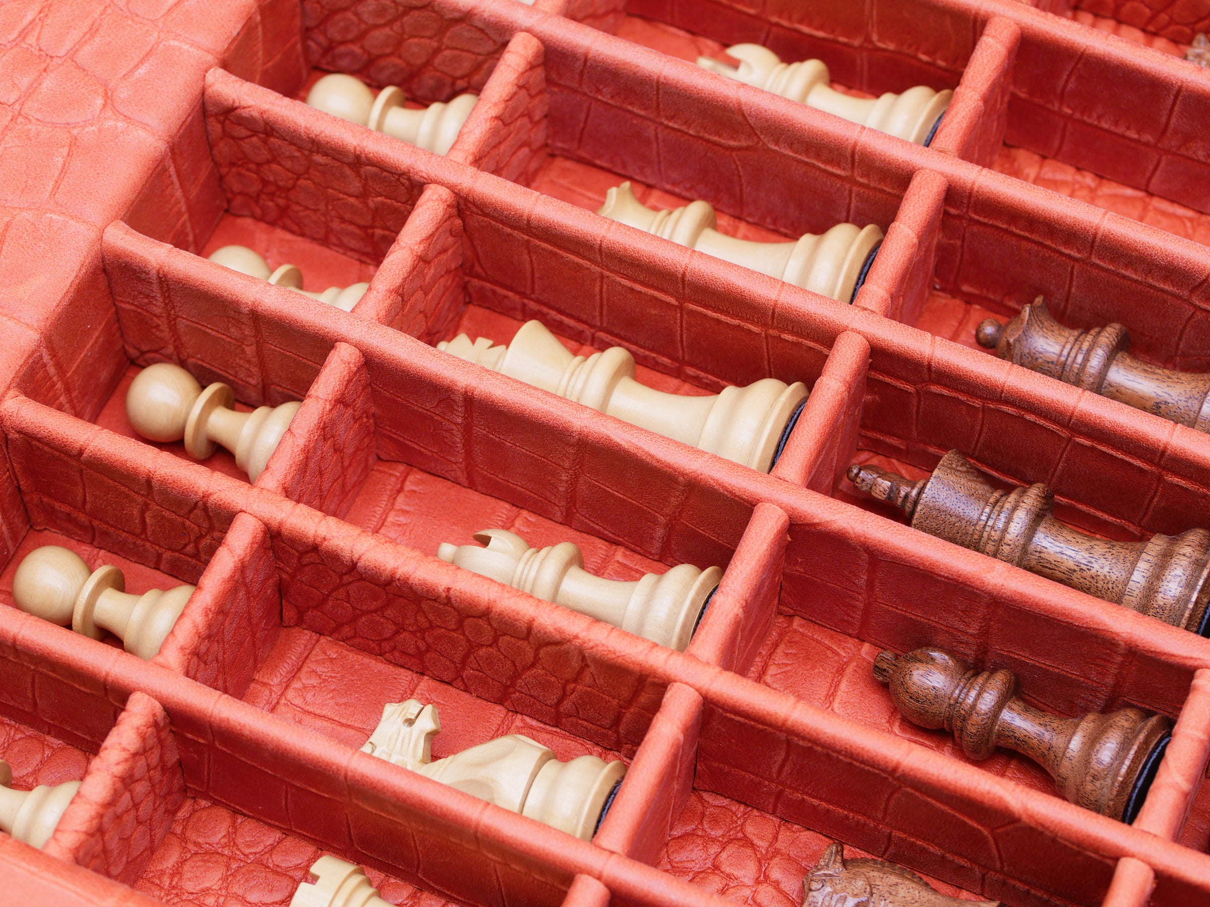 Red alligator-embossed leather chess box interior with cream and brown chess pieces in compartments