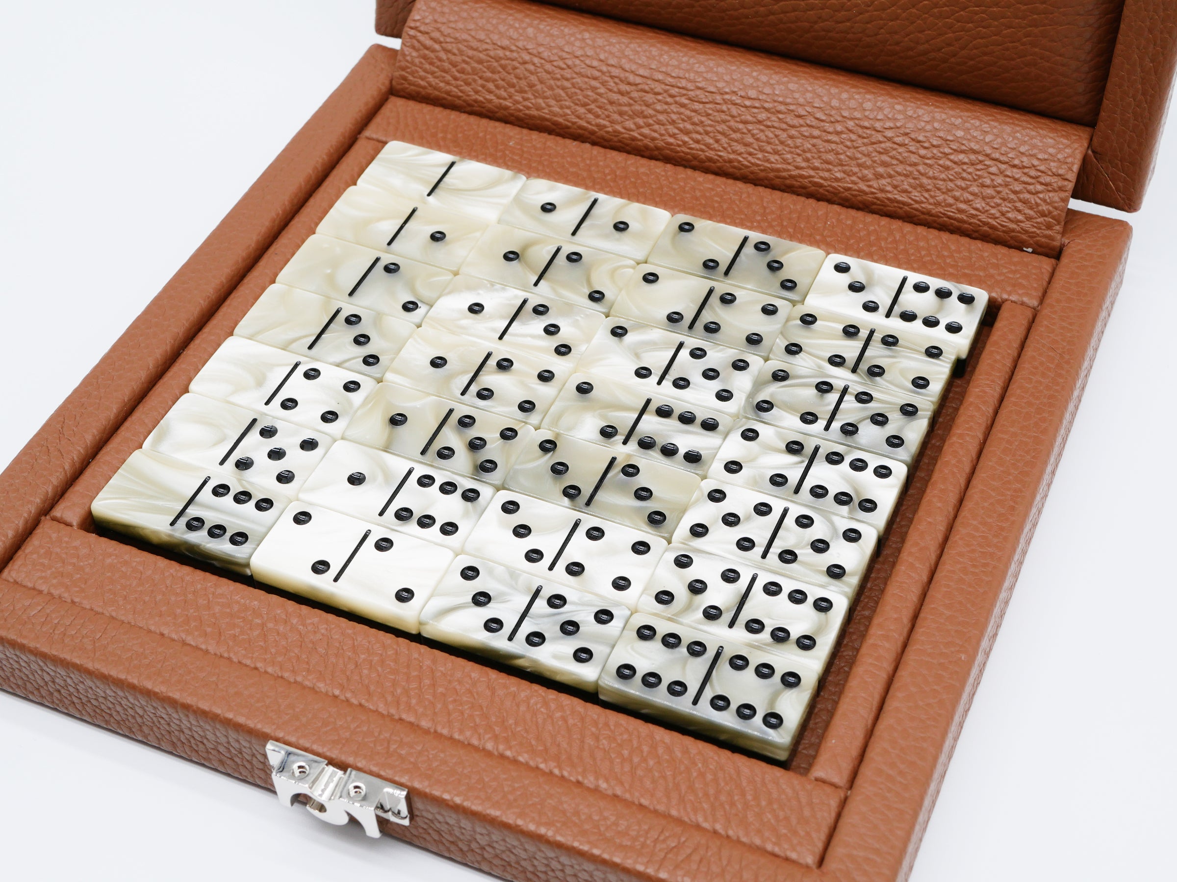 Open buffalo leather domino case with ivory domino tiles and black pips neatly arranged inside.