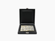 Open black leather domino box with ivory two tone domino tiles arranged inside