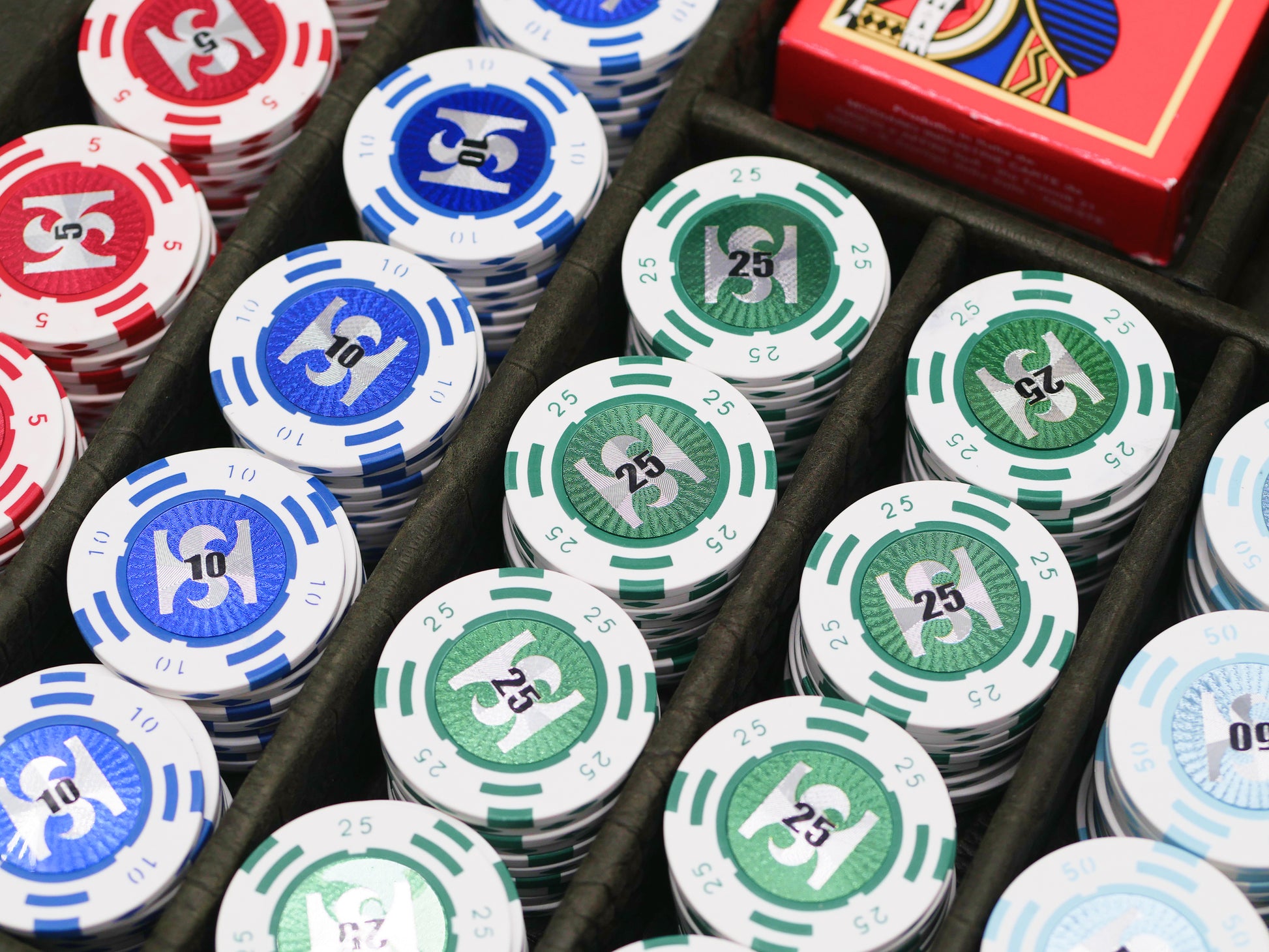 Top view of poker set in a black case with blue red and green chips and a red Modiano deck box